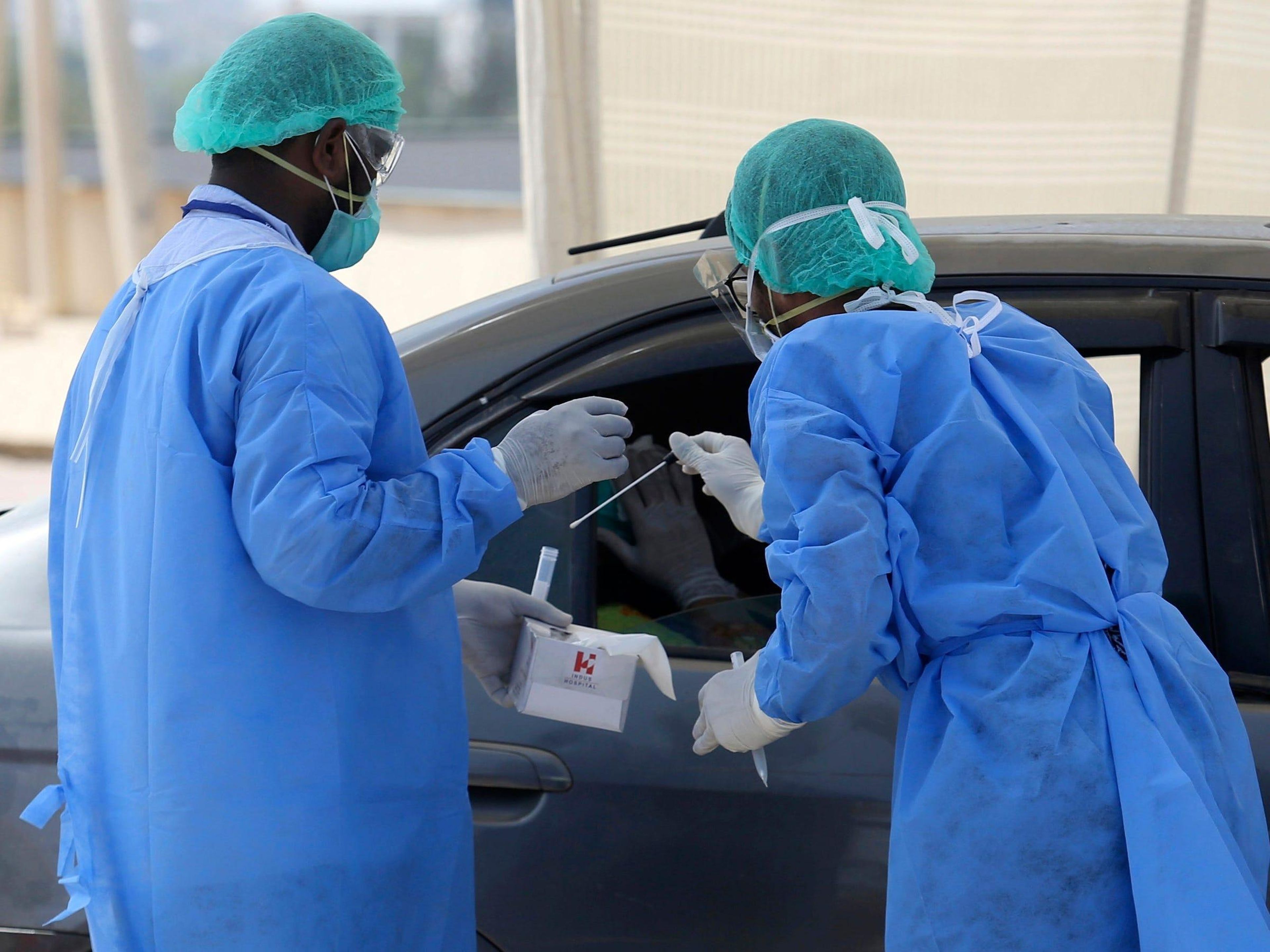 Los trabajadores sanitarios recogen una muestra en un centro de pruebas y detección de COVID-19 en Karachi, Pakistán, el 6 de abril de 2020.