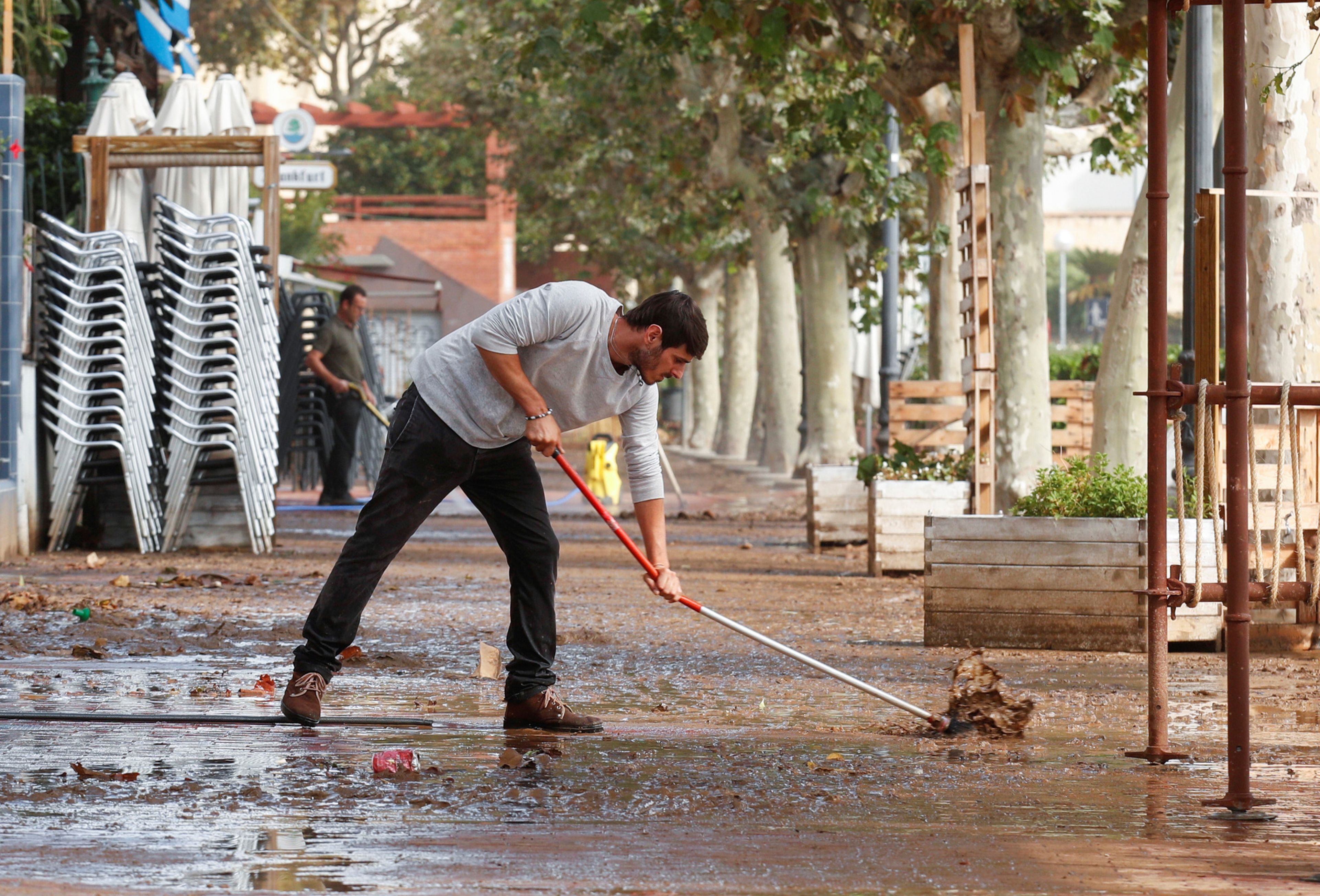 hombre limpiando agua calle, inundación