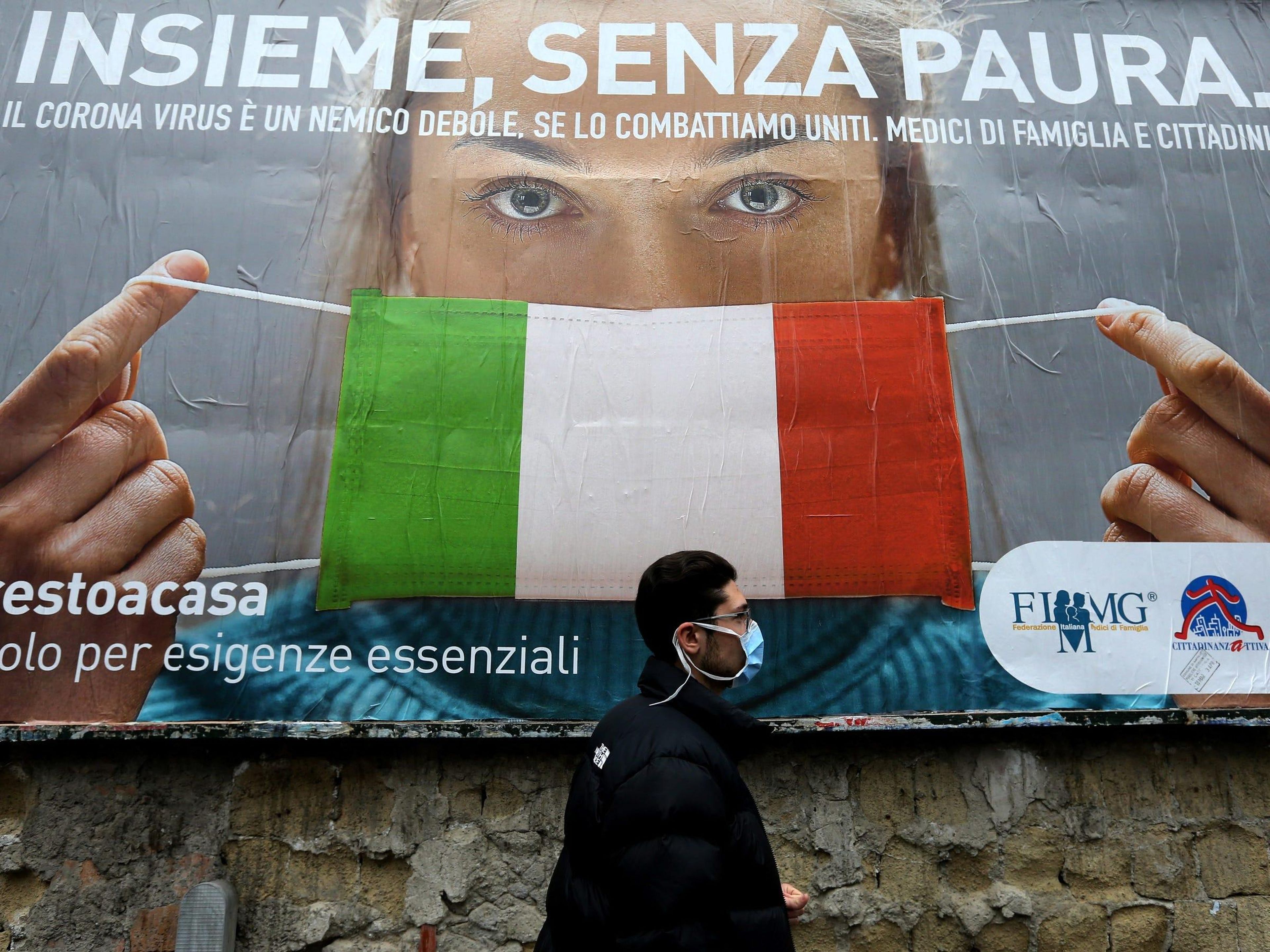 Un hombre pasa junto a una valla publicitaria sobre el nuevo coronavirus: "Juntos, sin miedo", Nápoles, Italia, 22 de marzo de 2020.
