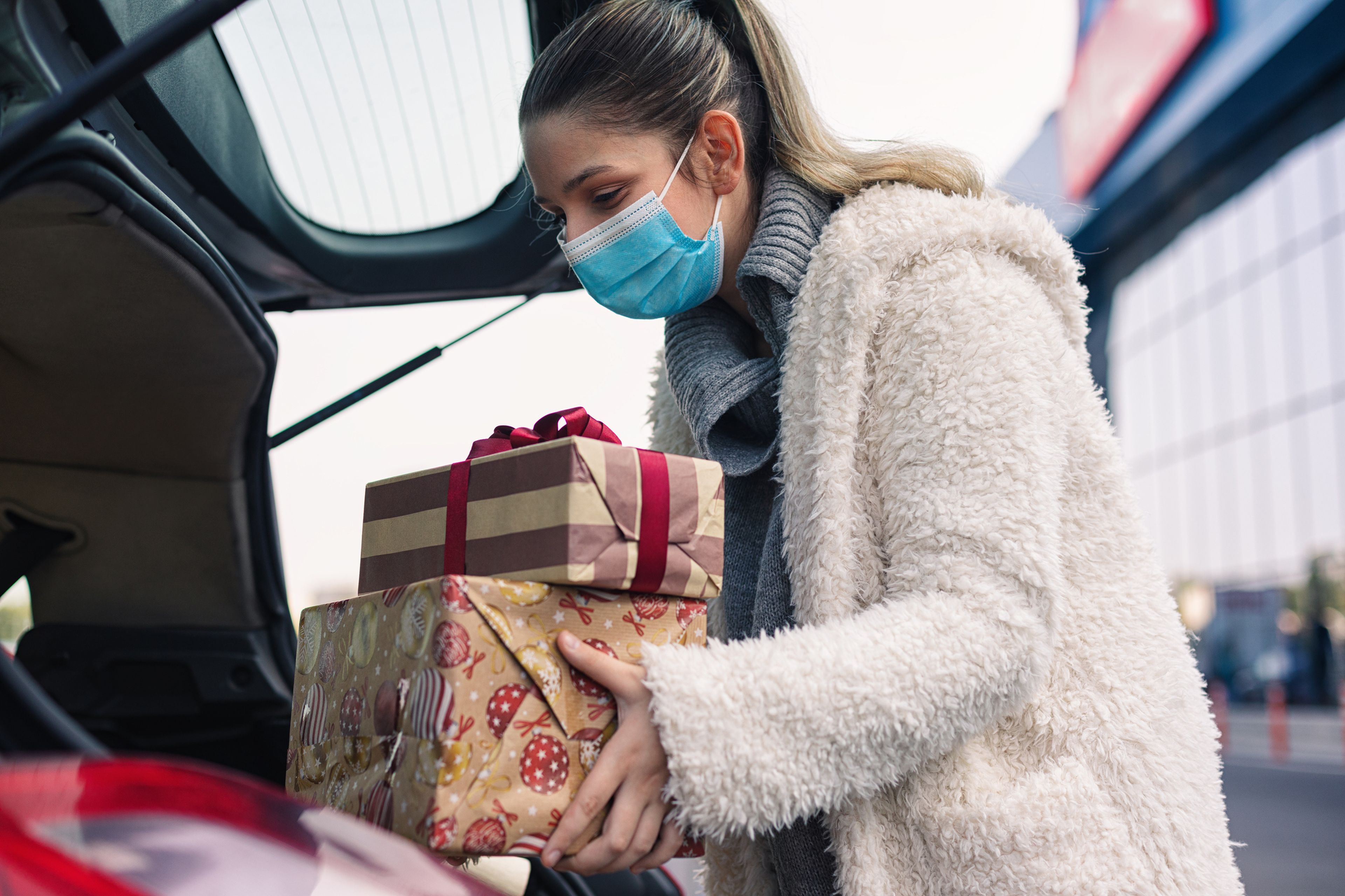 Mujer guardando regalos en el maletero del coche.