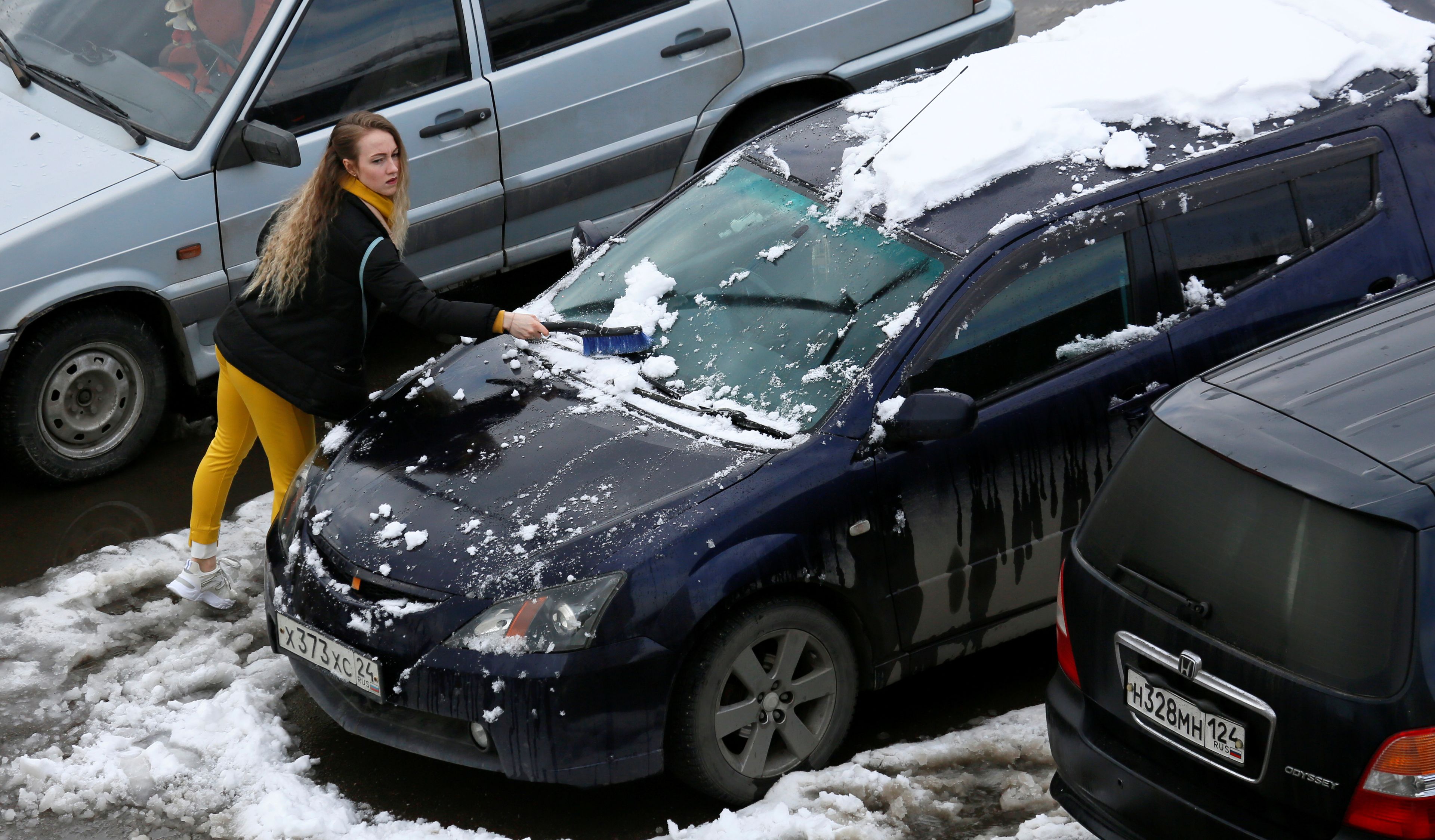 Mujer limpiando la nieve de su coche