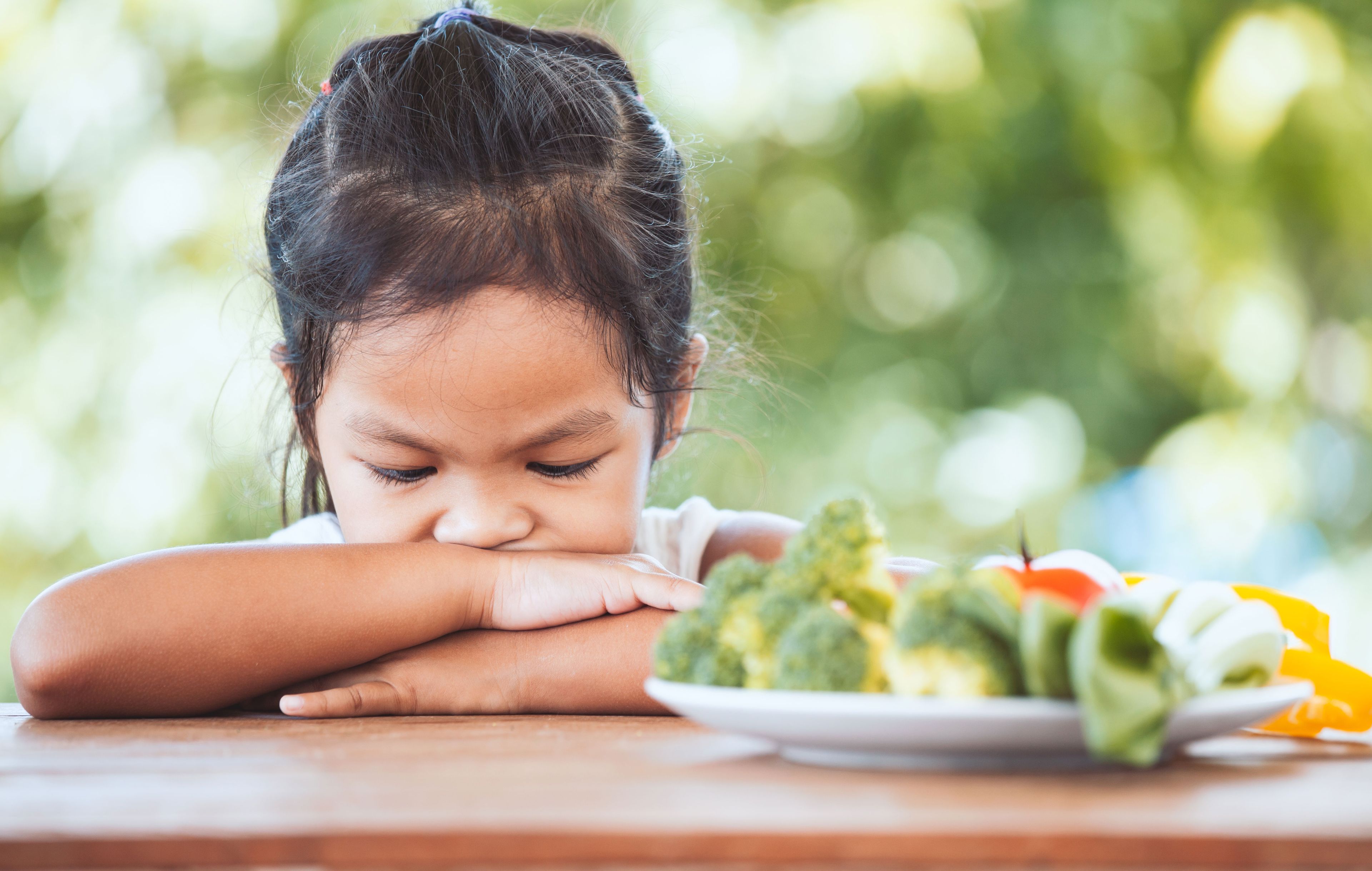 Una niña se apoya sobre sus manos con el plato de comida lleno.
