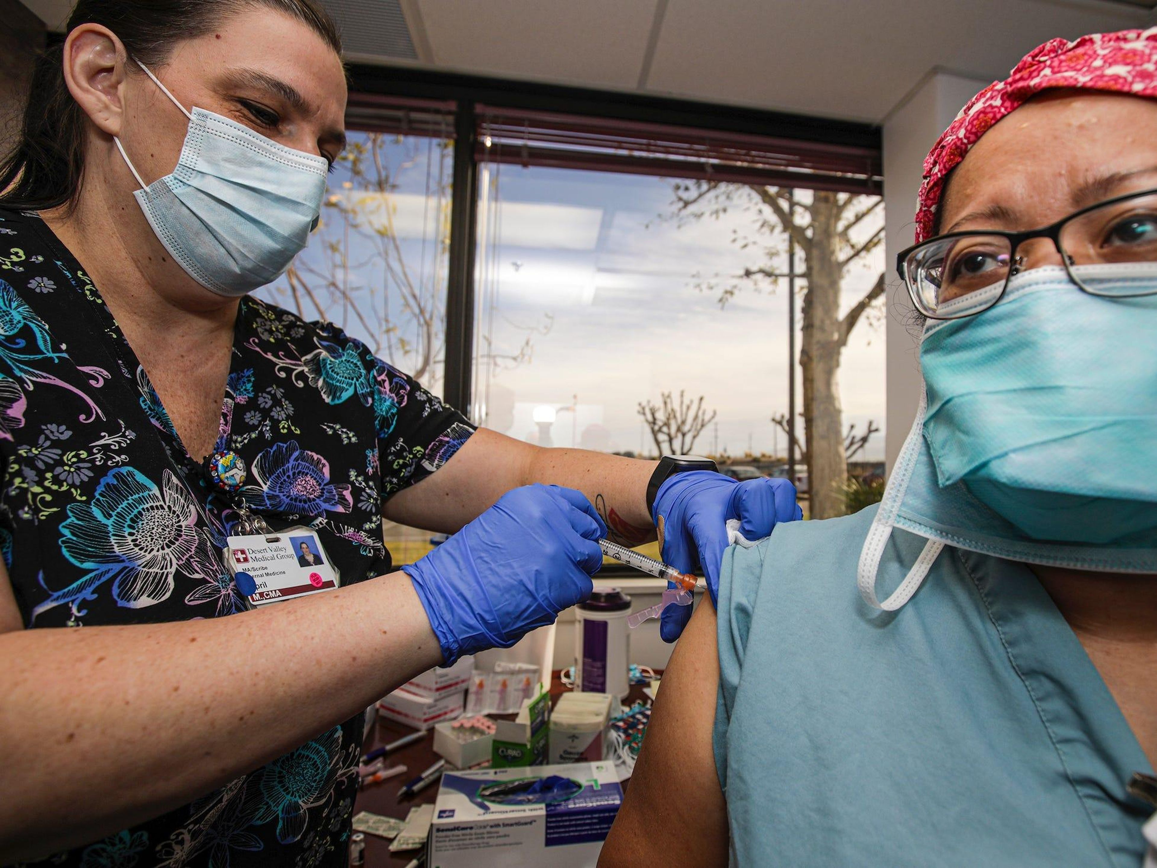 La asistente médica April Massaro da la primera dosis de la vacuna COVID-19 de Pfizer y BioNTech a la enfermera Alice Fallago, en el Hospital Desert Valley, el jueves 17 de diciembre de 2020, en Victorville, California, EEUU.
