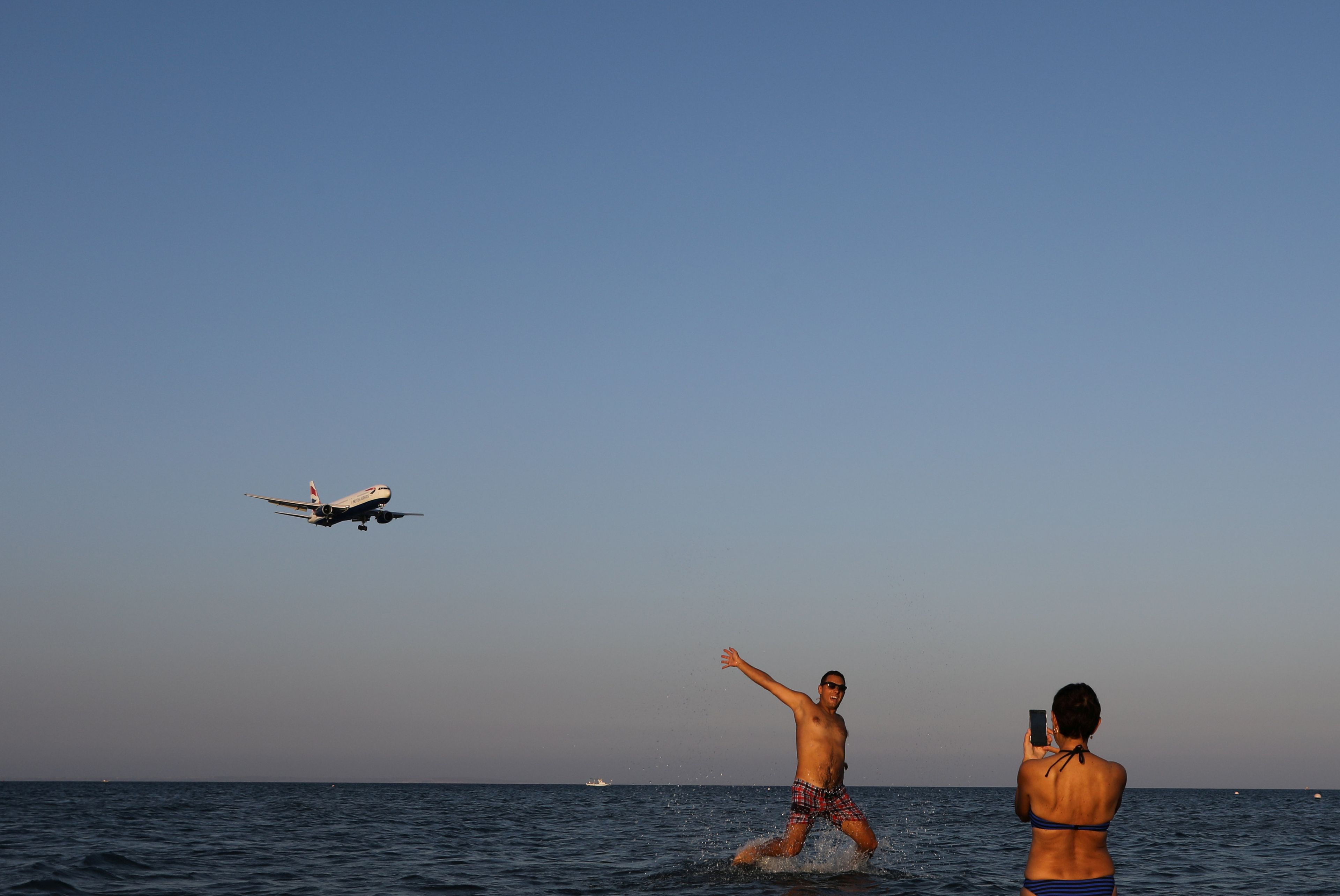 Turistas en la playa se hacen fotos con un avión que va a aterrizar en el Aeropuerto Internacional de Lárnaca.