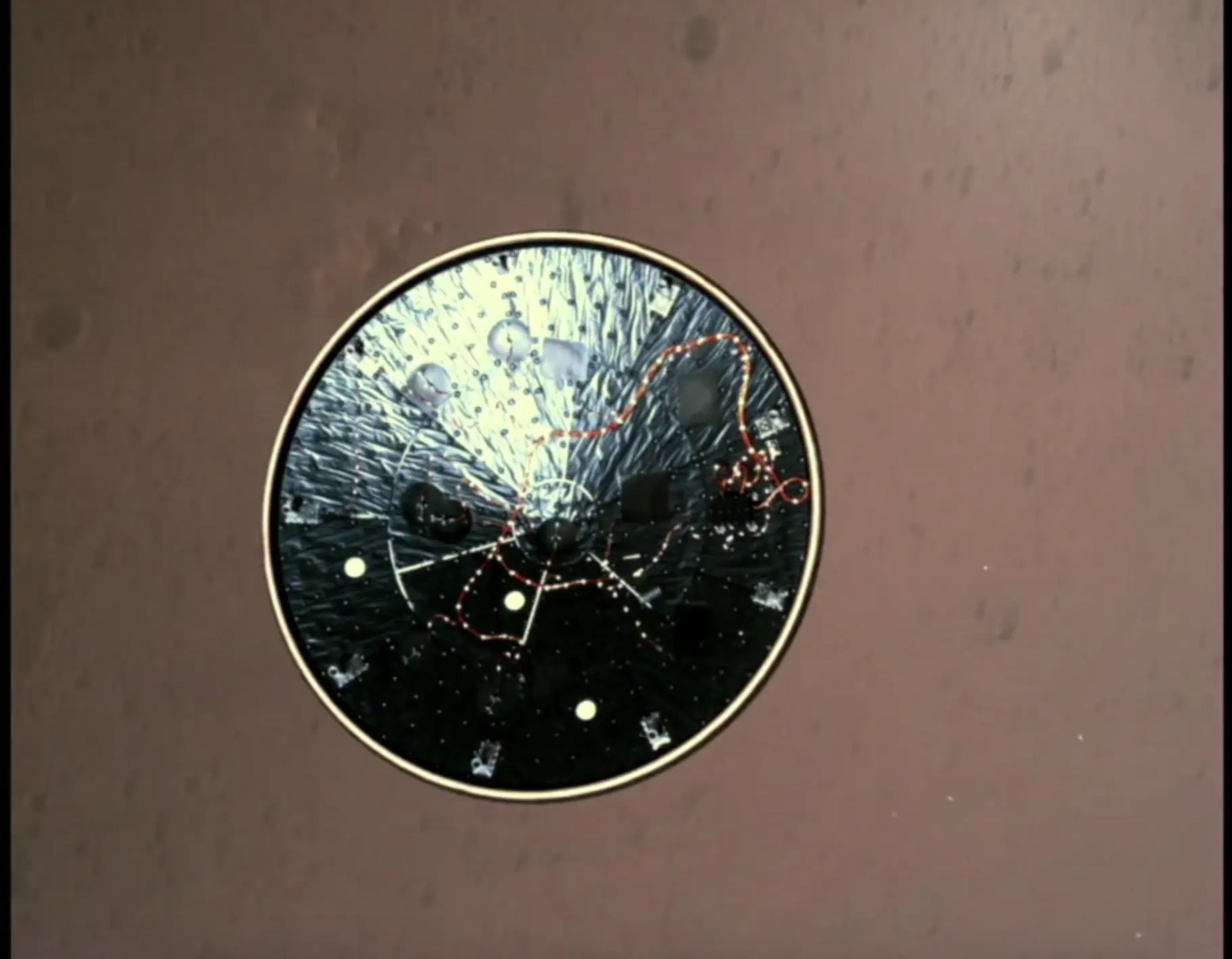Una captura de pantalla del vídeo de aterrizaje del Perseverance muestra el escudo térmico cayendo, exponiendo una cámara en el vientre del rover, mientras desciende a Marte.