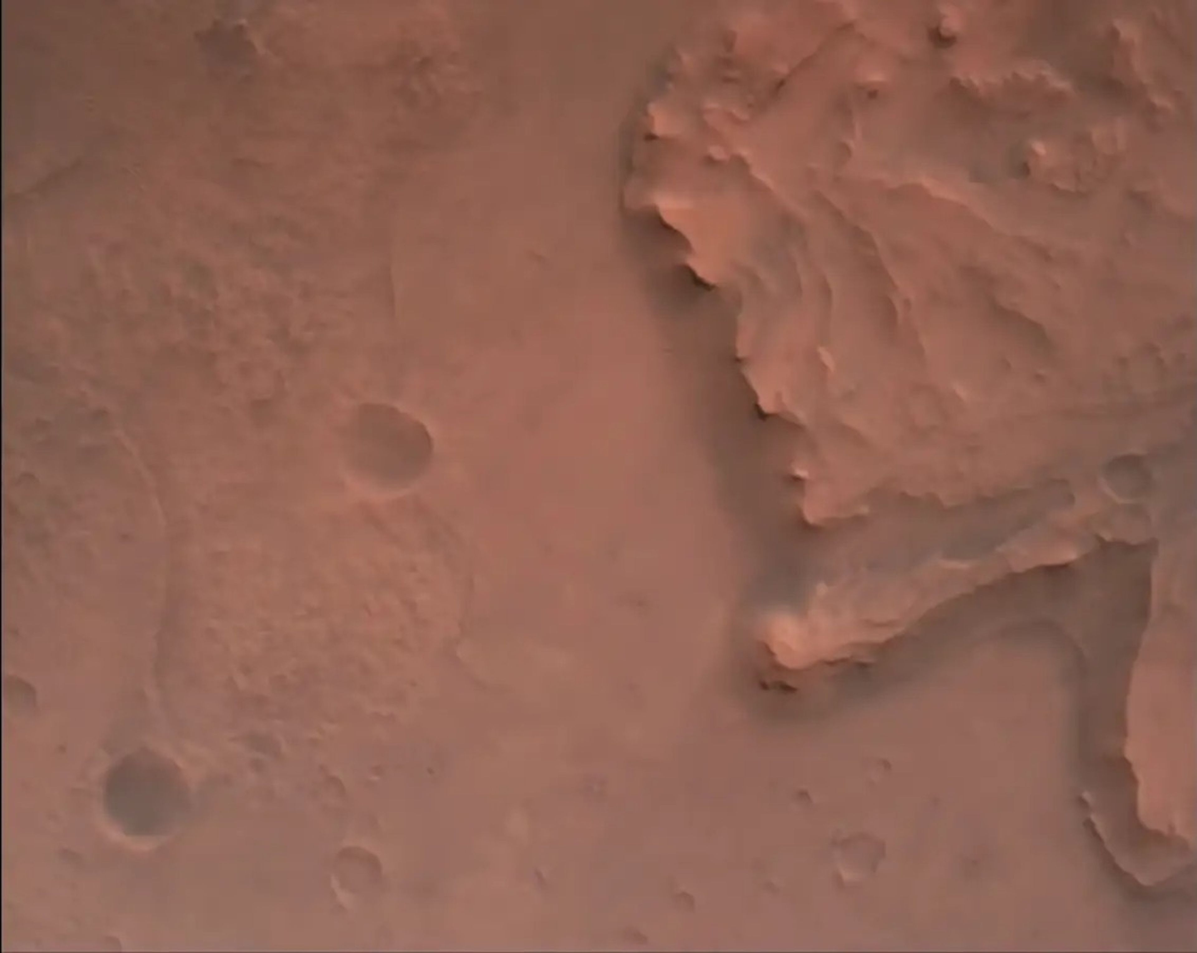 Una captura de pantalla del vídeo de descenso y aterrizaje del rover Perseverance muestra el cráter Jezero, con los acantilados de 60 metros del delta del río a la derecha.