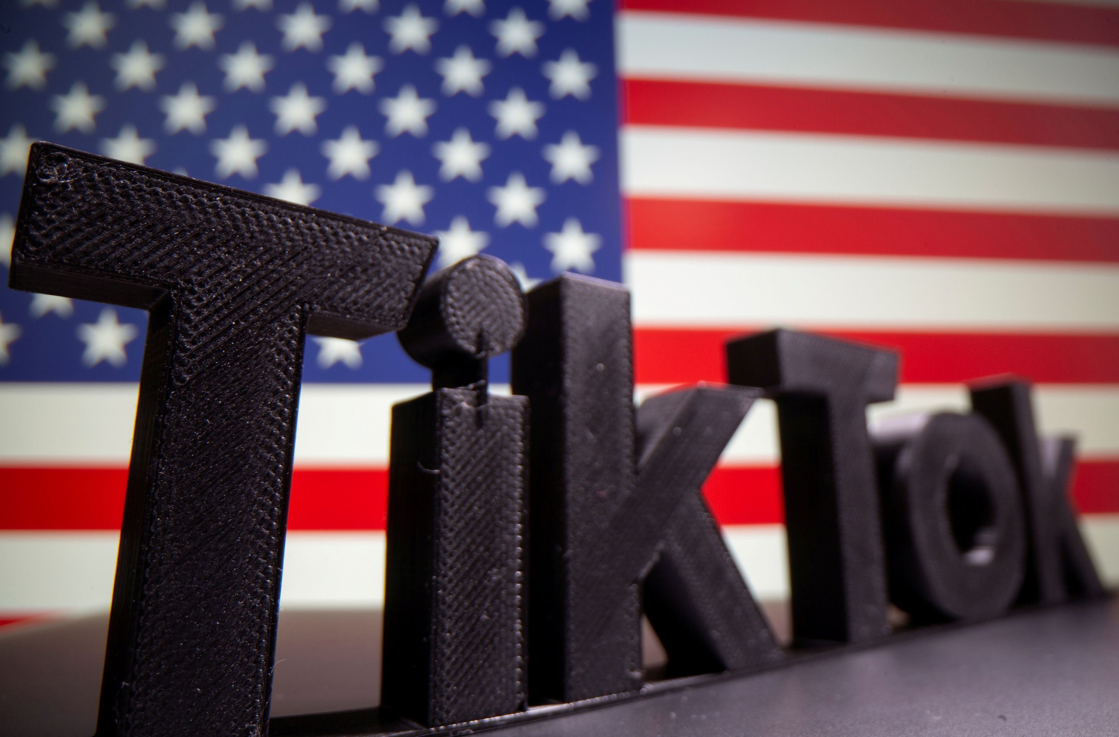 Logotipo en 3D de TikTok delante de una bandera de Estados Unidos.