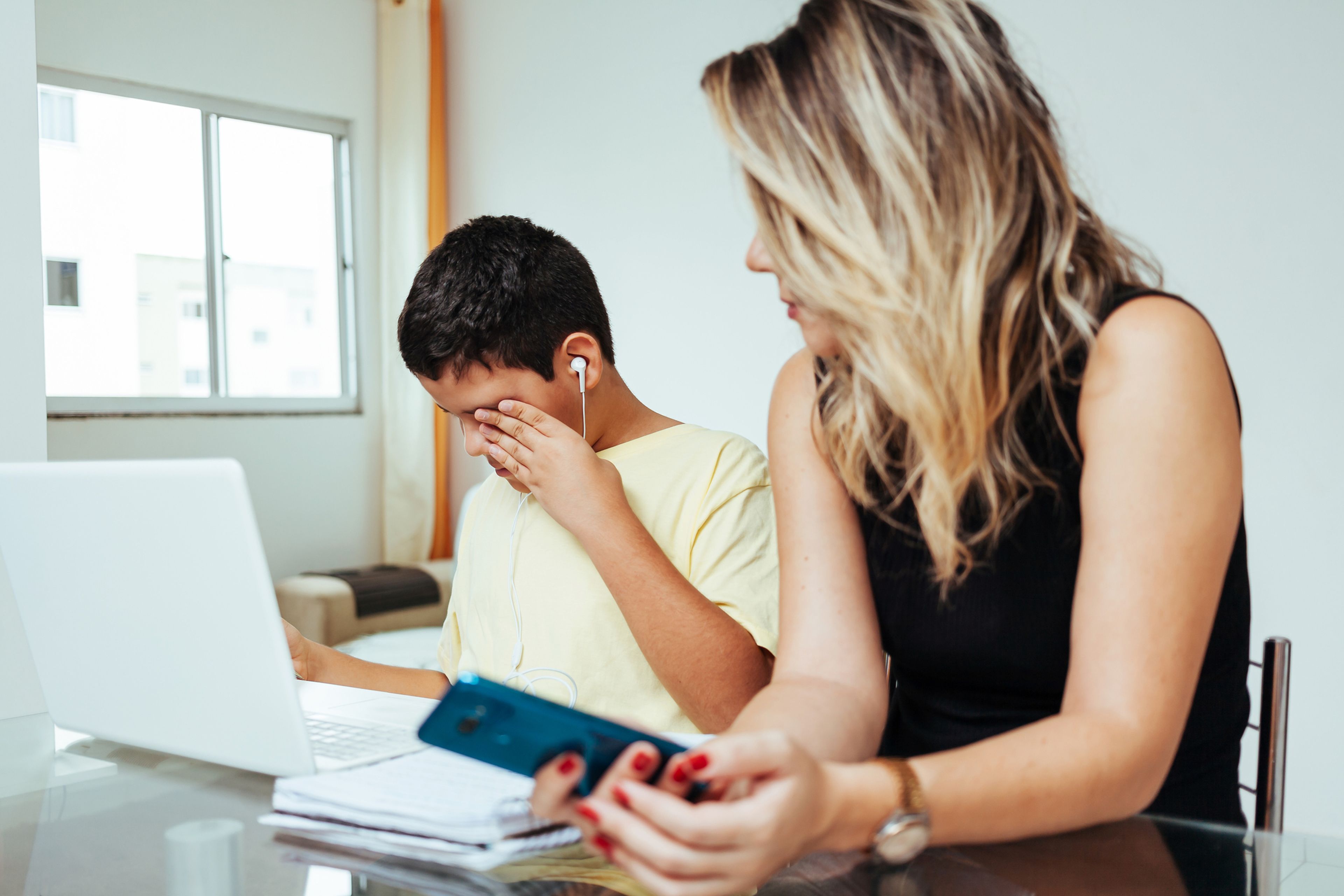 Una madre trata de ayudar a su hijo (que está llorando) a hacer los deberes