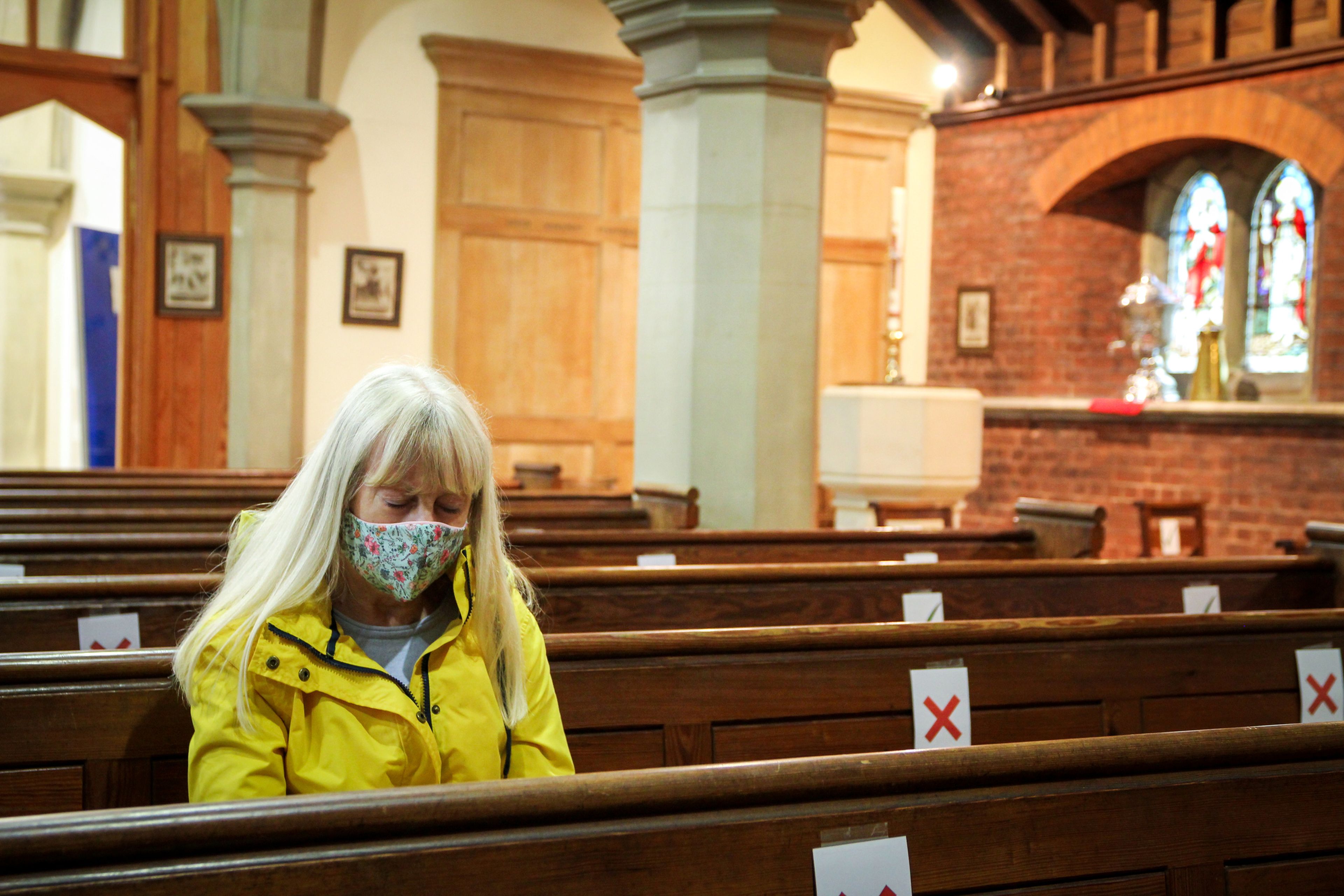 Una mujer en una iglesia con mascarilla.