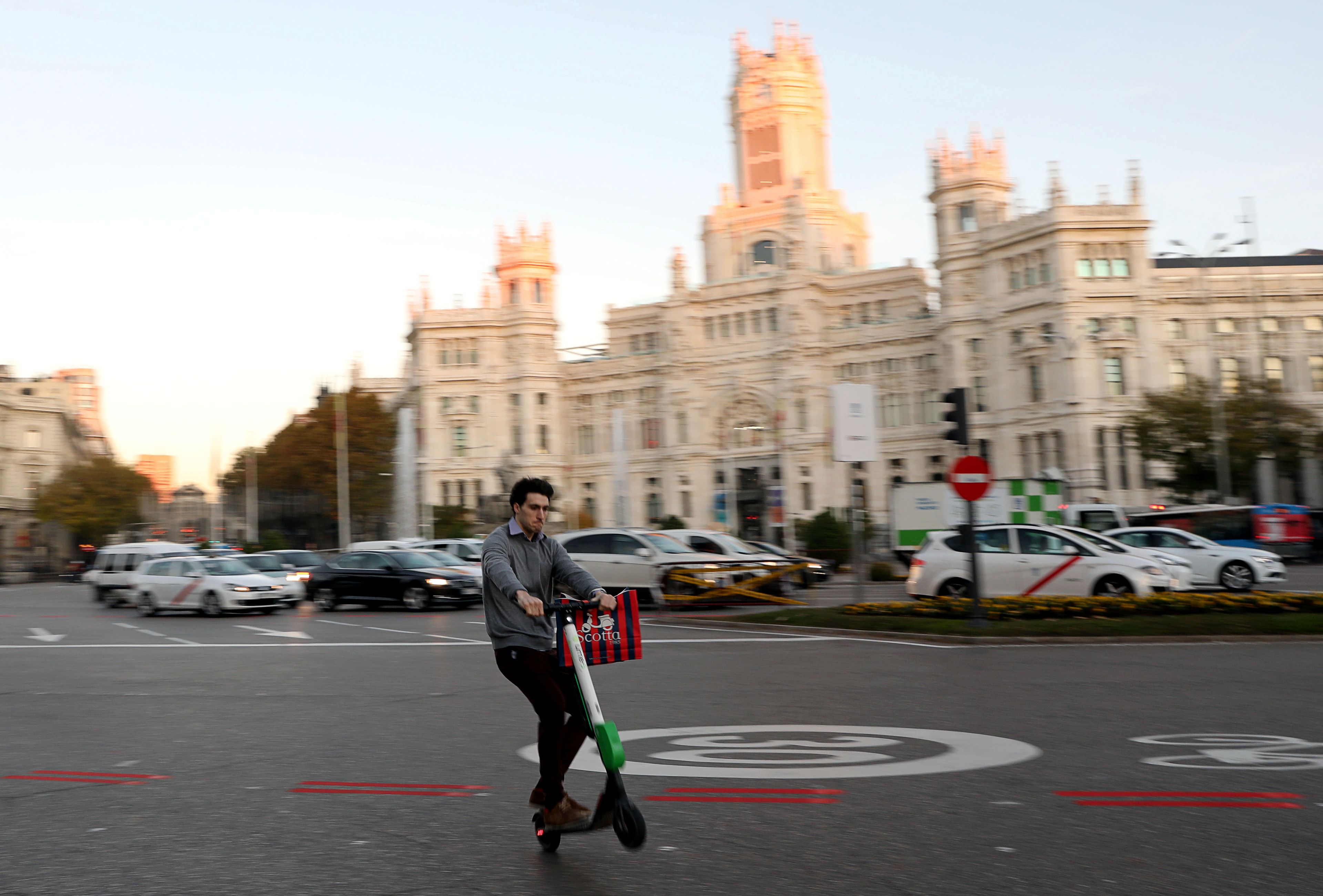 Un patinete eléctrico compartido de la marca estadounidense Lime pasa por delante del Ayuntamiento de Madrid.