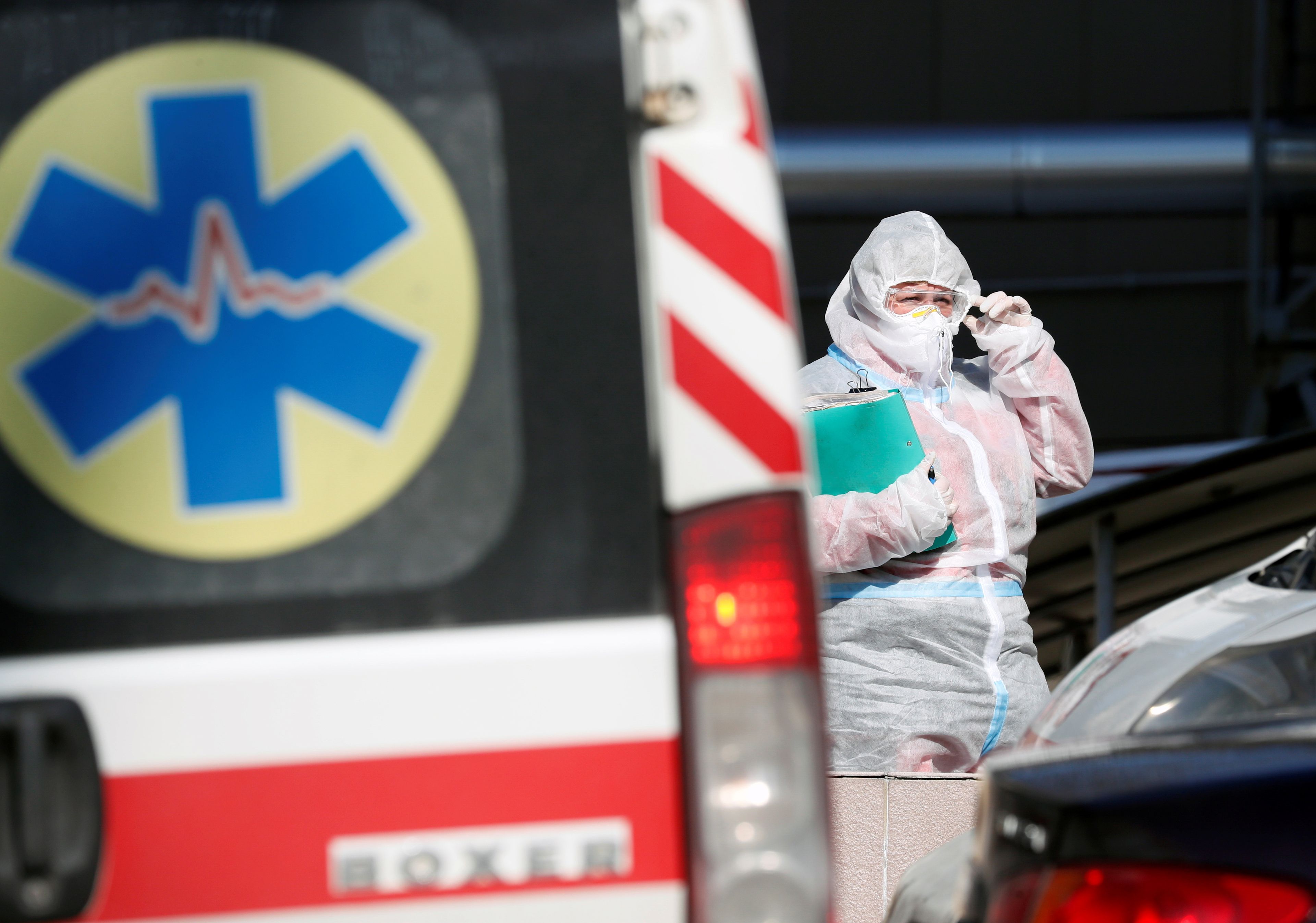 Un trabajador sanitario con EPI cerca de una ambulancia.