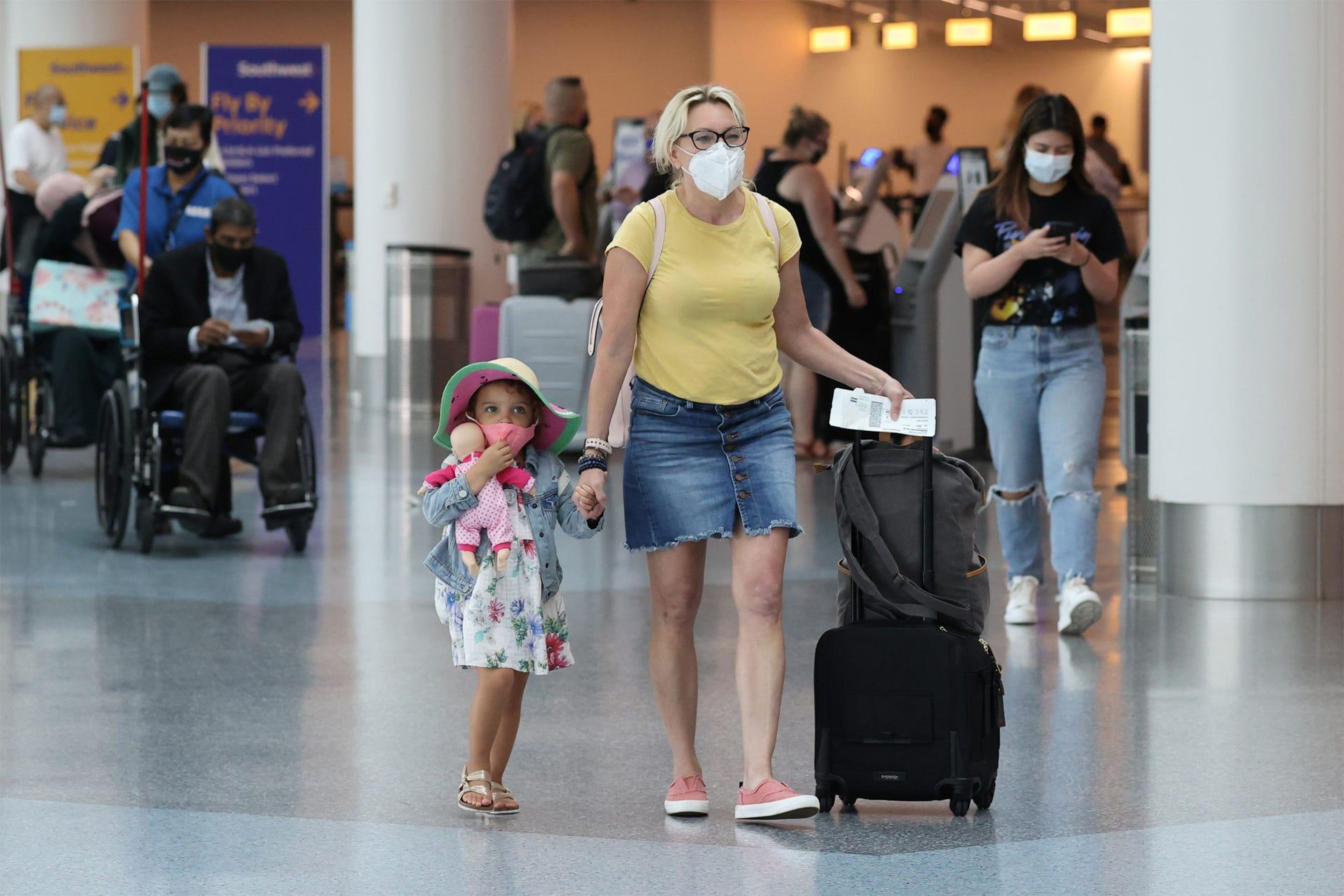 Pasajeros con mascarillas mientras caminan por el Aeropuerto Internacional de Los Ángeles.