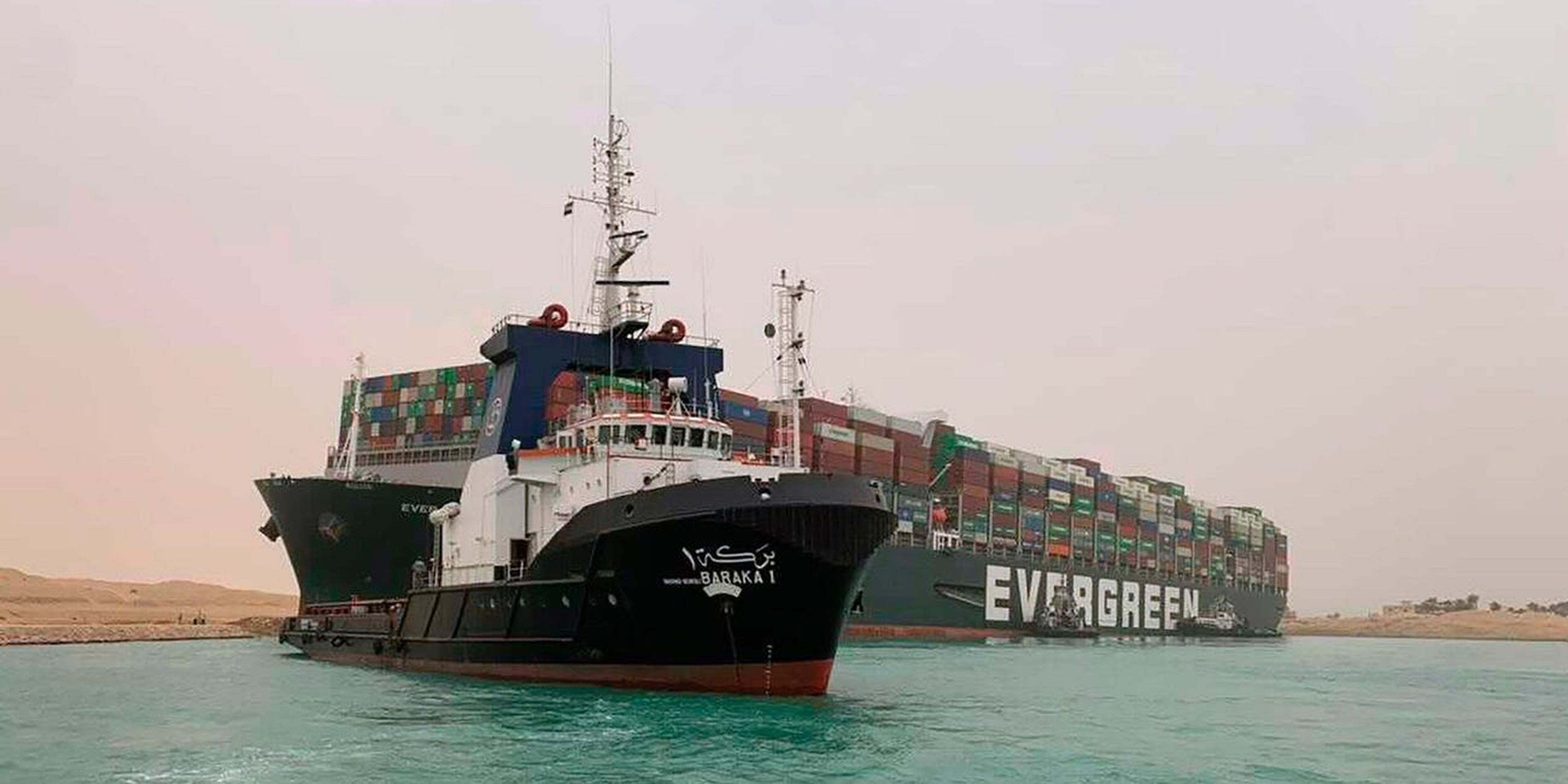 Un barco navega ante un enorme portacontenedores llamado Ever Given, varado el miércoles 24 de marzo de 2021 en el Canal de Suez, Egipto.