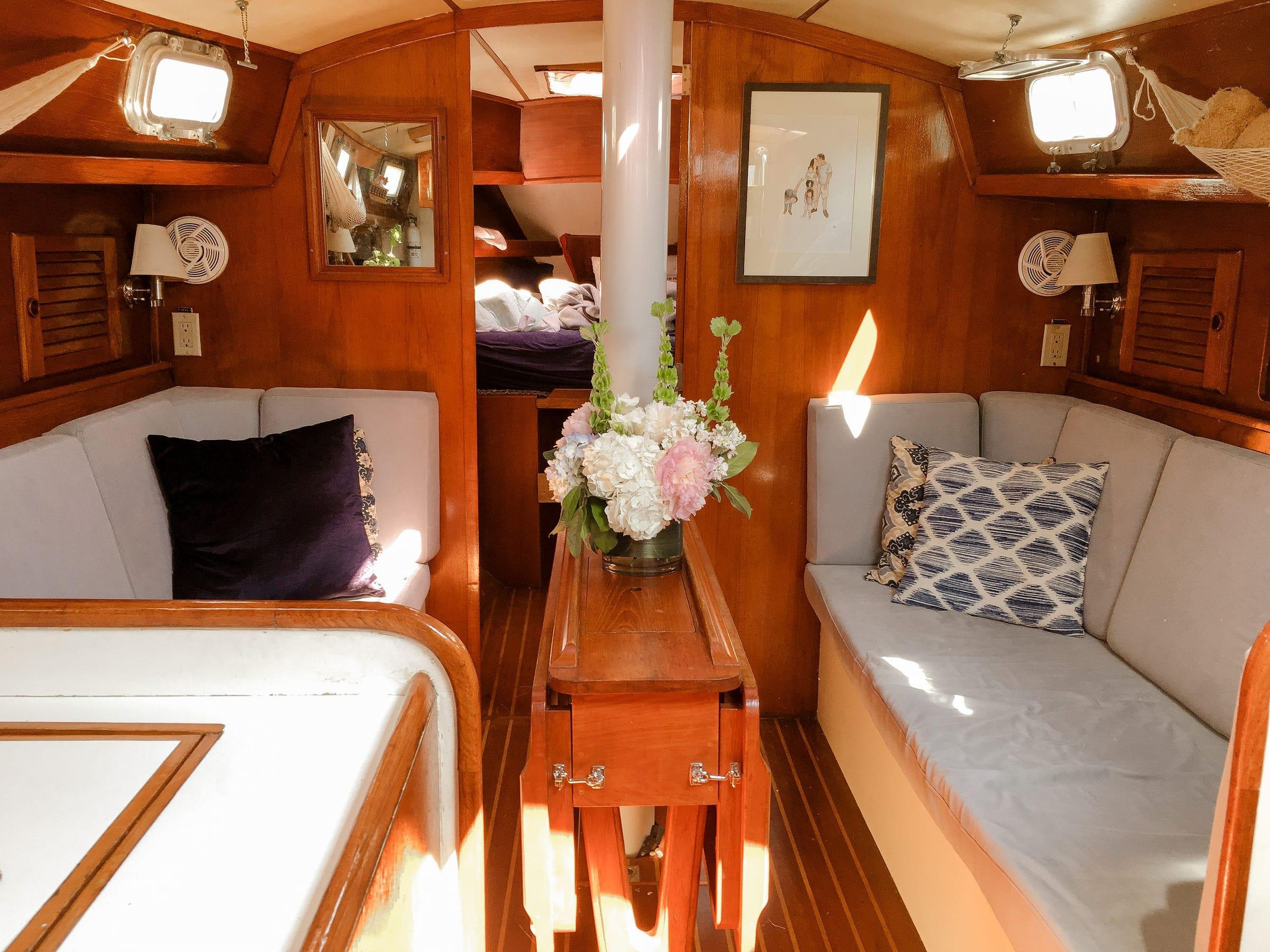 El velero que compraron tiene 2 dormitorios, un baño, una cocina y 2 sofás alrededor de una mesa.