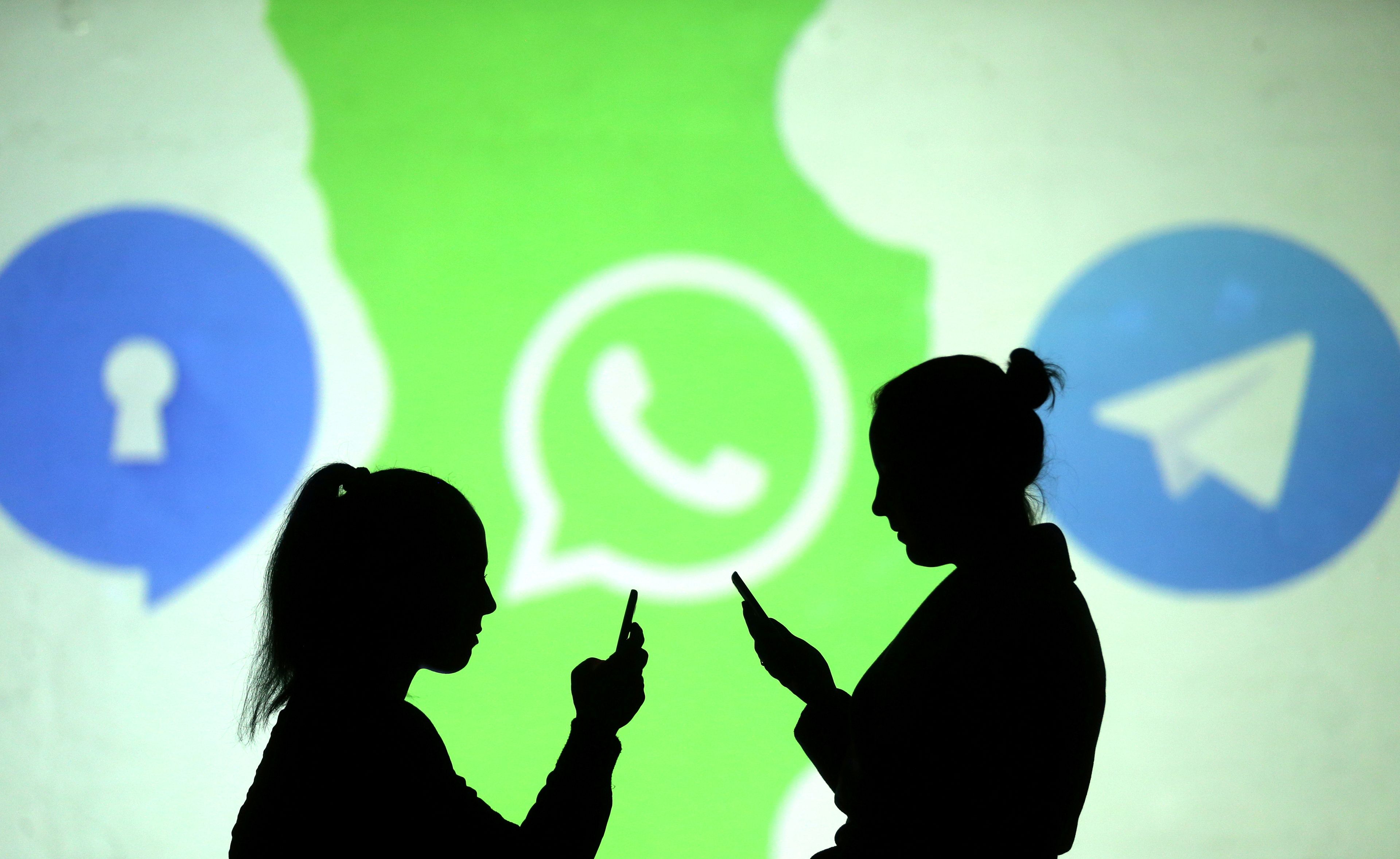 Dos siluetas caminando delante de un logo de WhatsApp