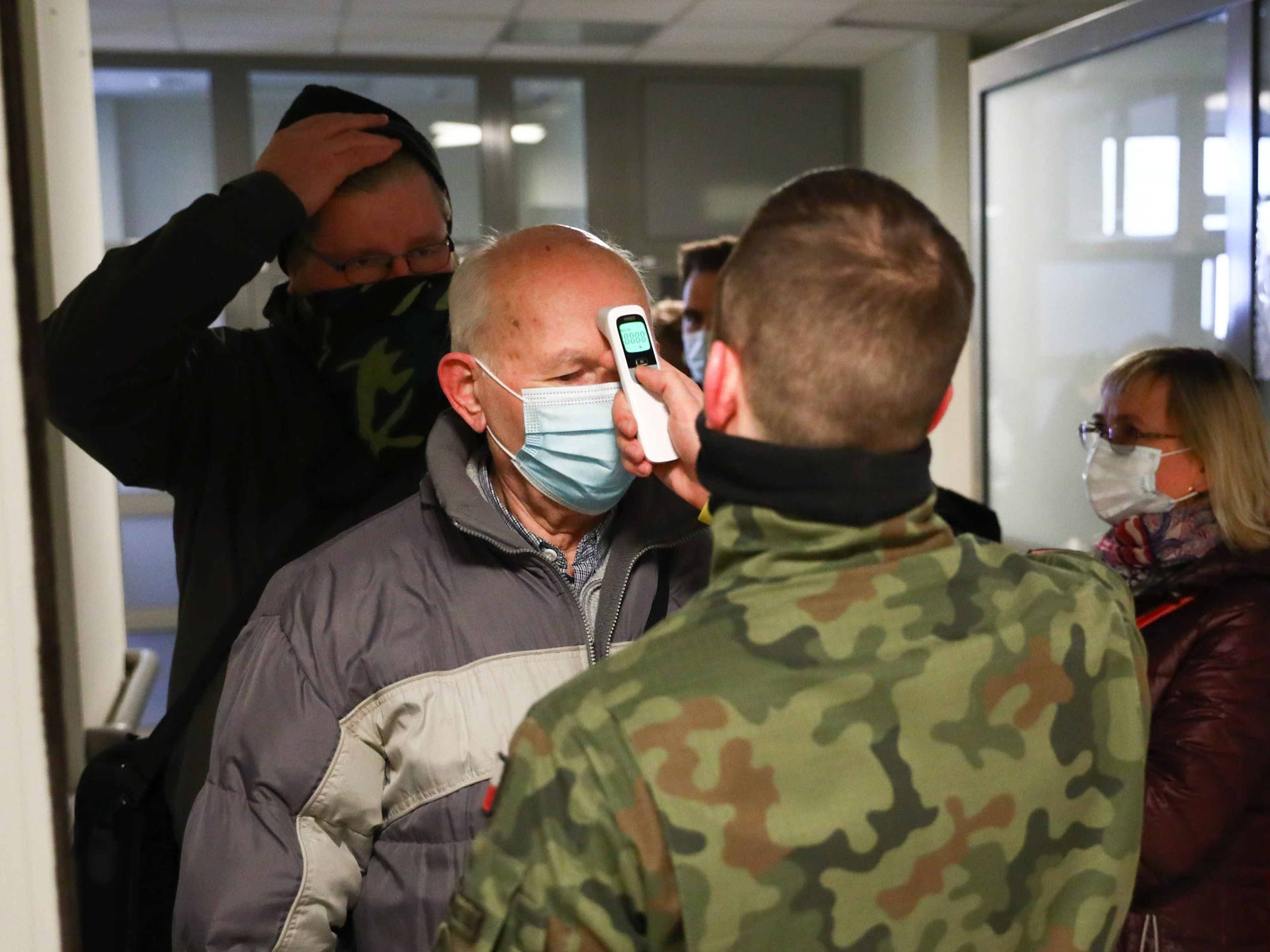 Un hombre al que le están tomando la temperatura en Hospital Universitario de Cracovia el primer día del programa de vacunación Covid-19 de los profesores