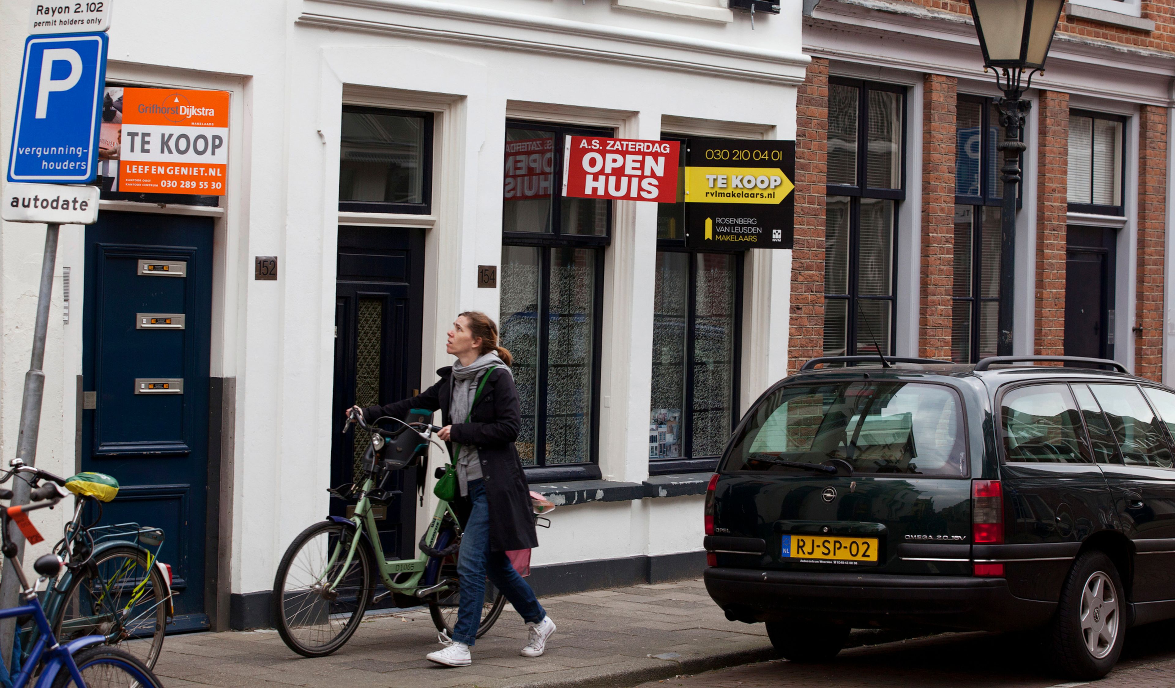 Una mujer con bicicleta pasa ante varias viviendas en venta en el centro de Amsterdam