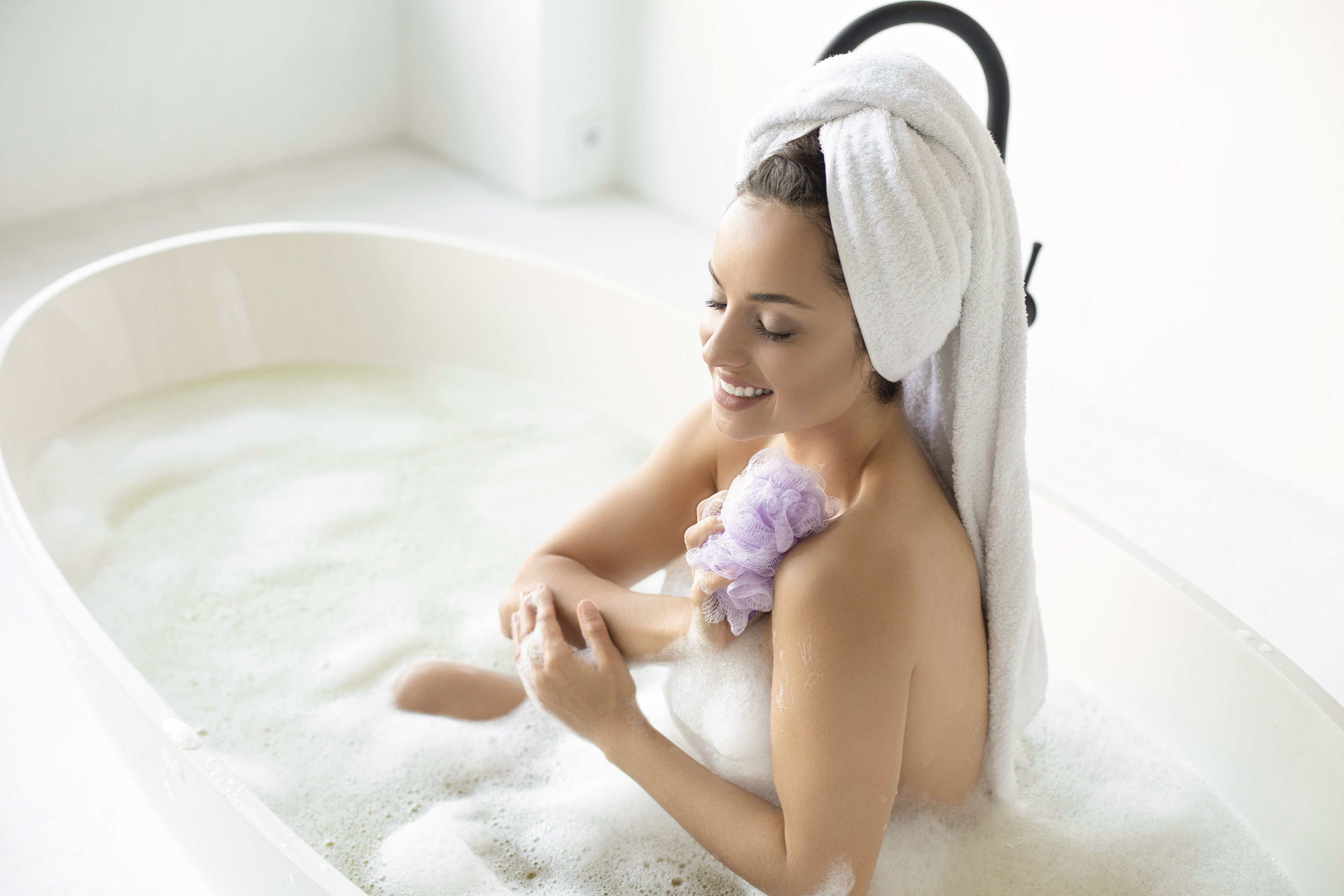 Mujer lavándose con una esponja de baño.