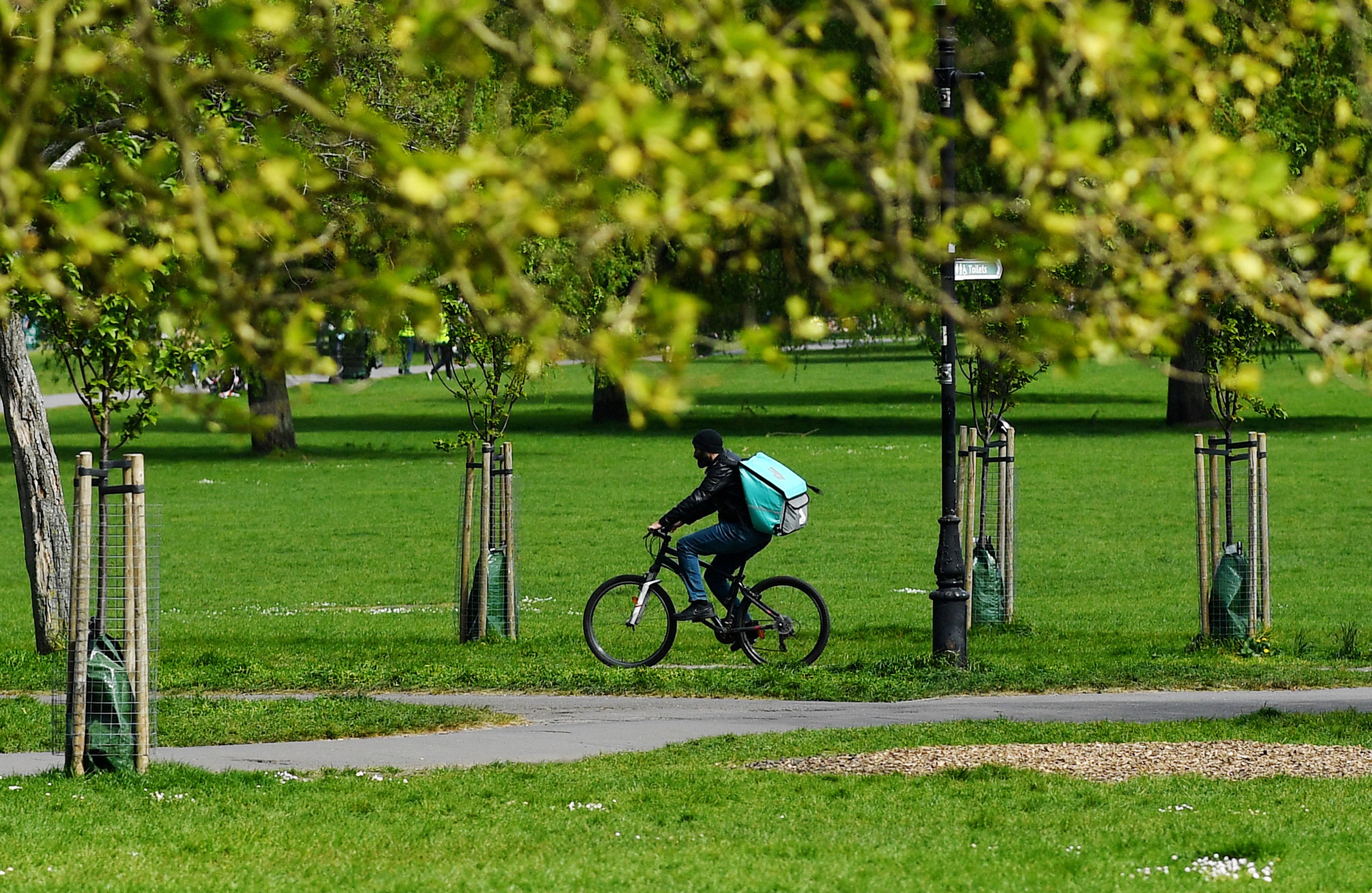 Un repartidor de Deliveroo circula por un parque en Londres