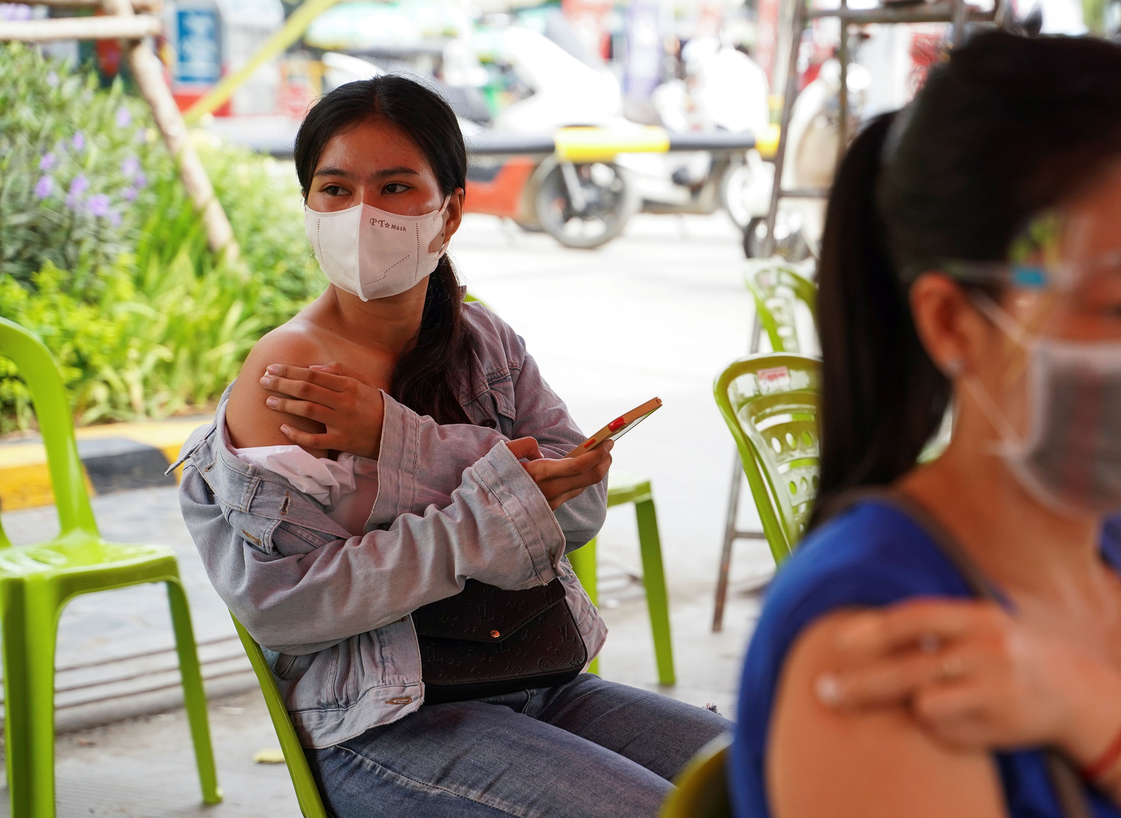 Una chica espera tras recibir la vacuna contra el COVID-19.