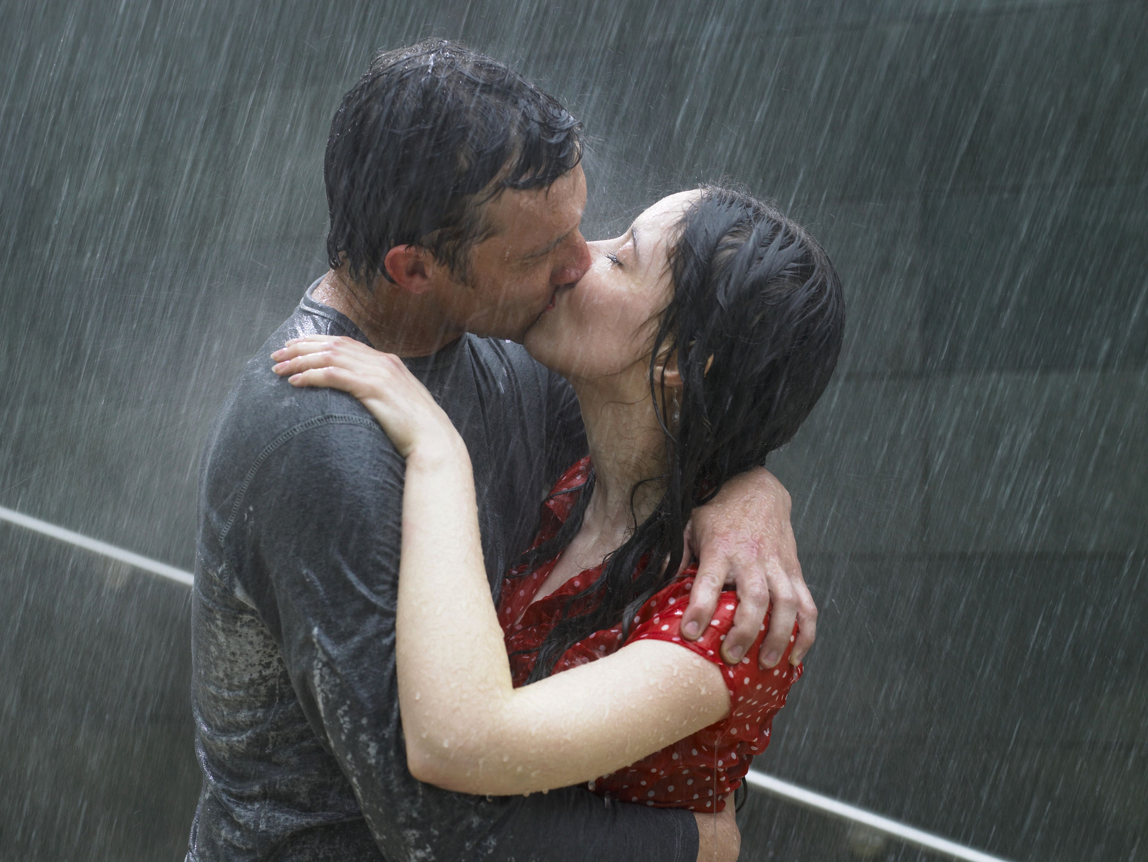 Dos personas se besan bajo la lluvia.