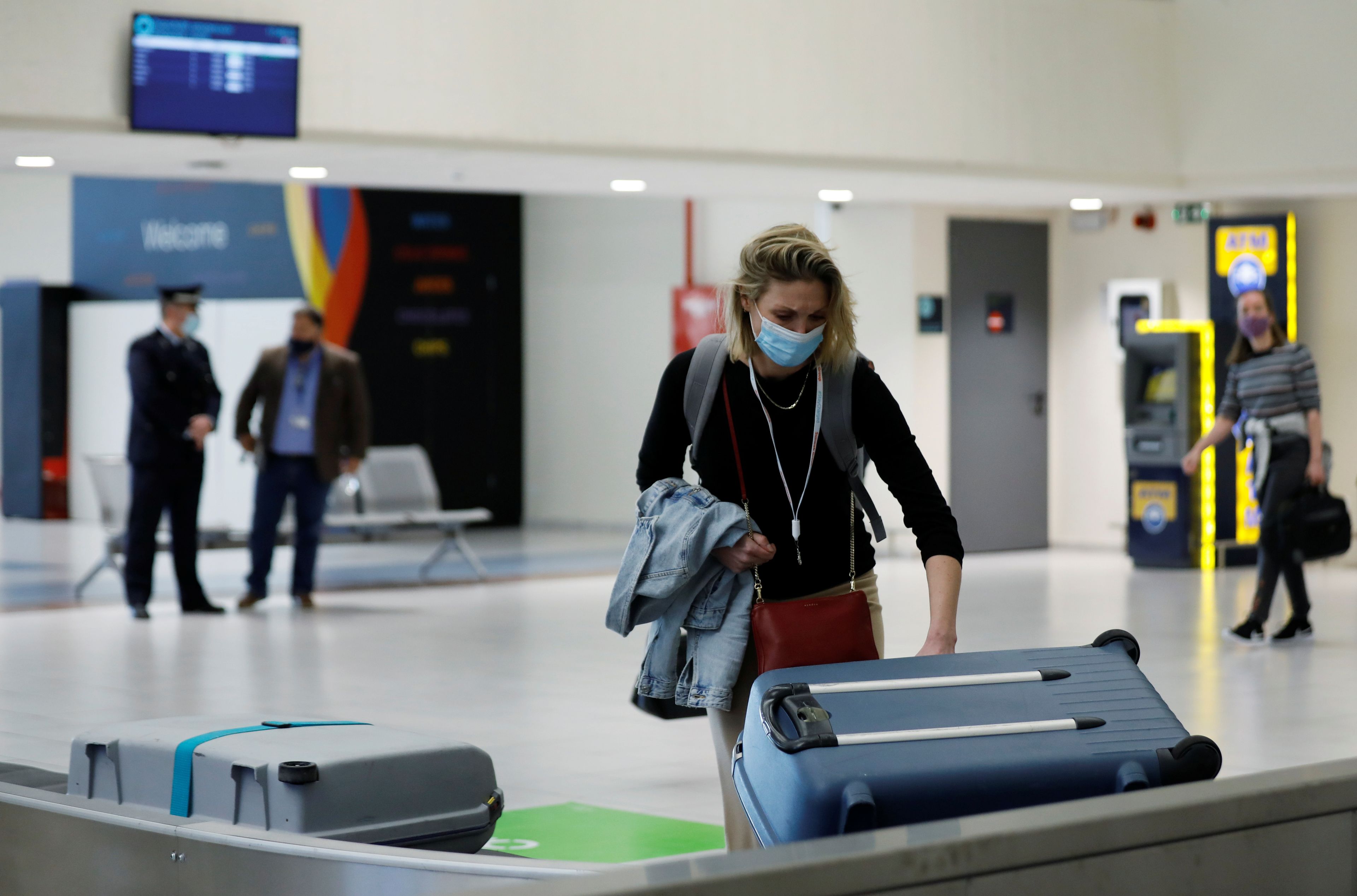 Una mujer recoge una maleta en la cinta del aeropuerto.