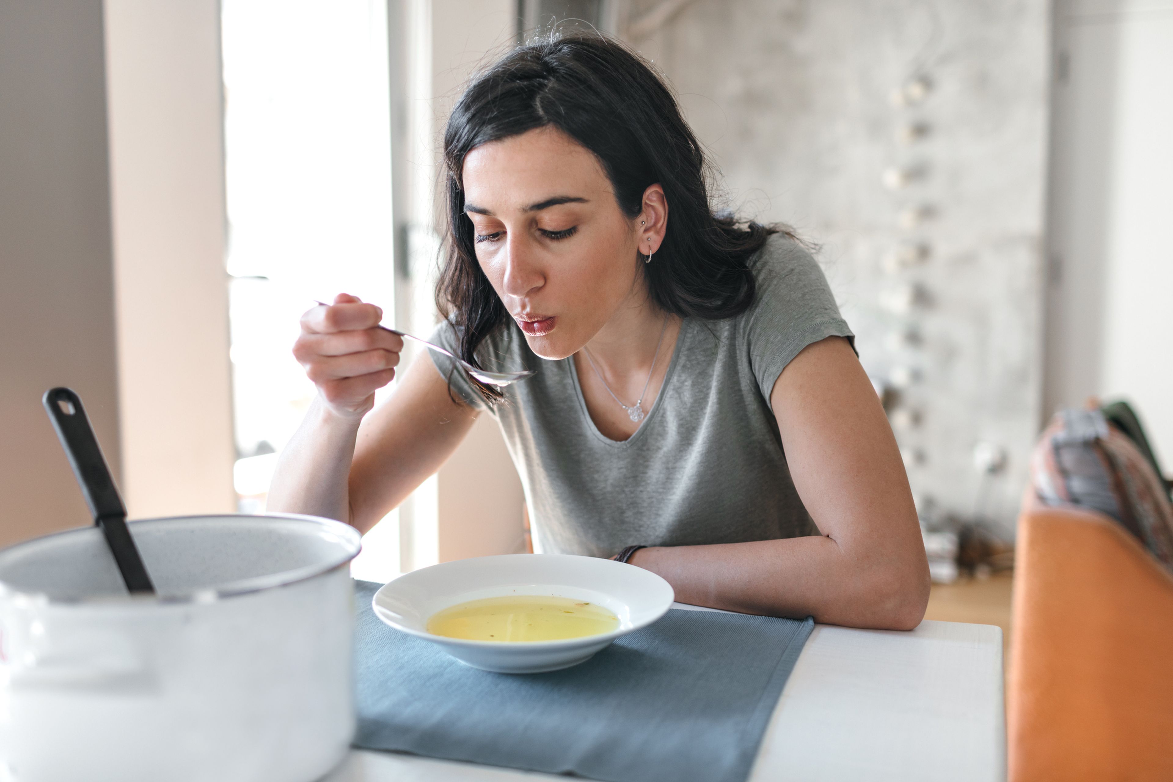 Una mujer toma sopa.