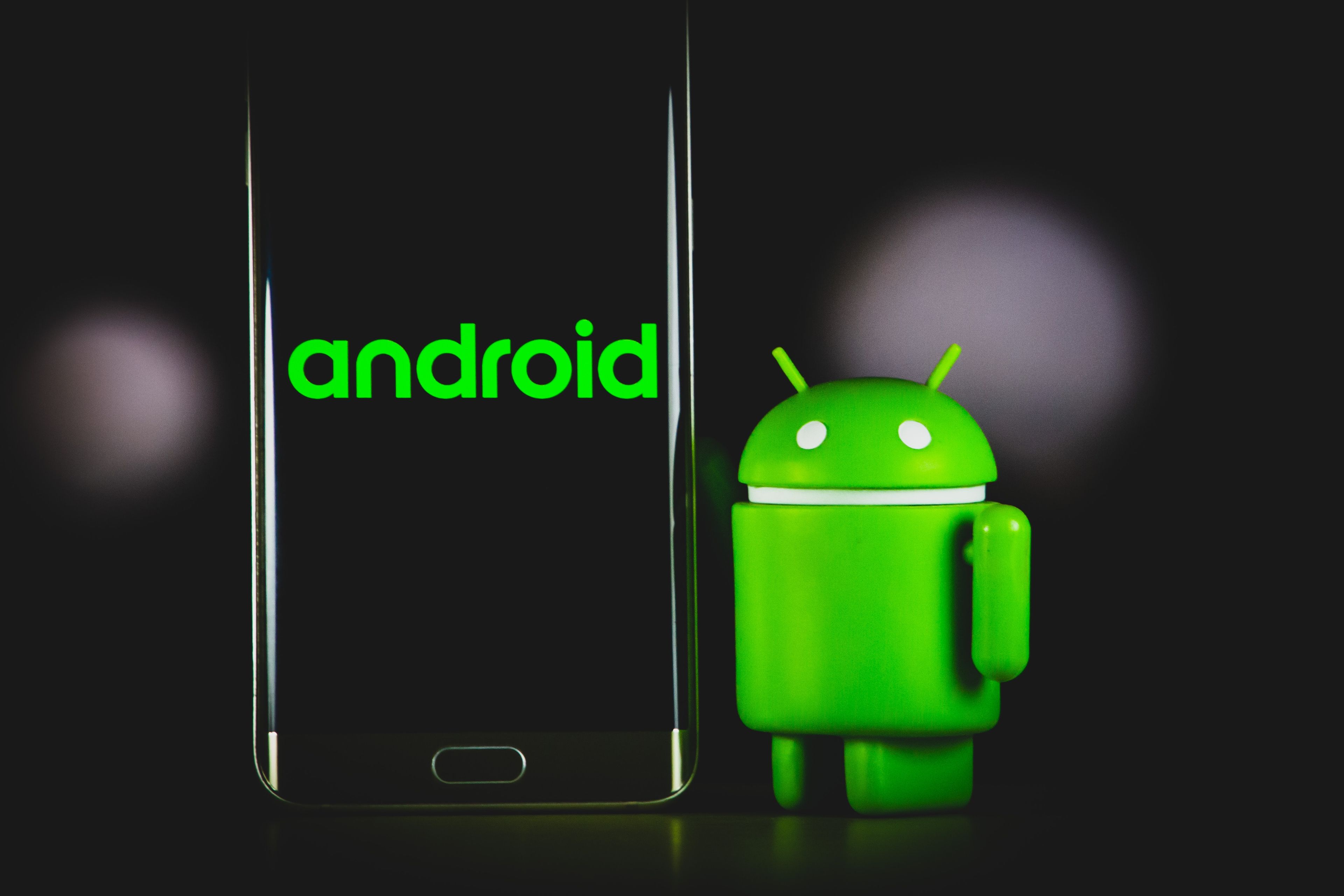 Un muñeco de Android al lado de un móvil