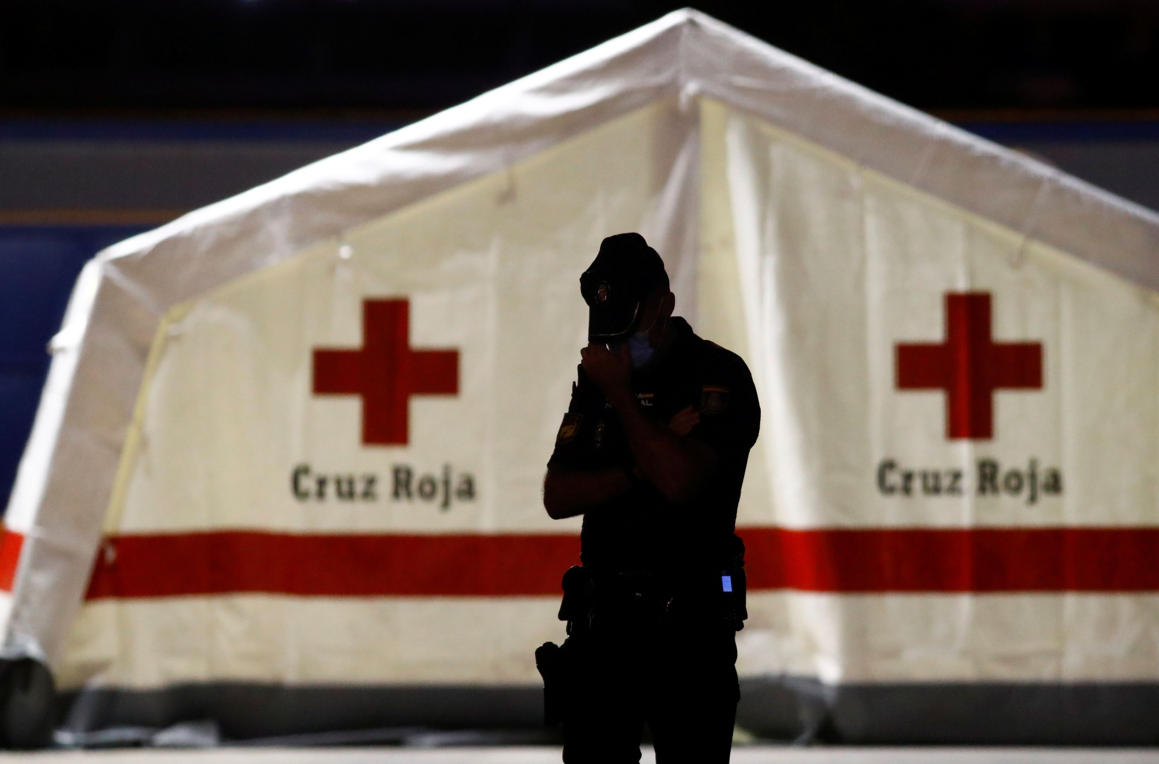 Un policía custodia una carpa de la Cruz Roja con cuerpos de inmigrantes muertos encontrados en un barco.