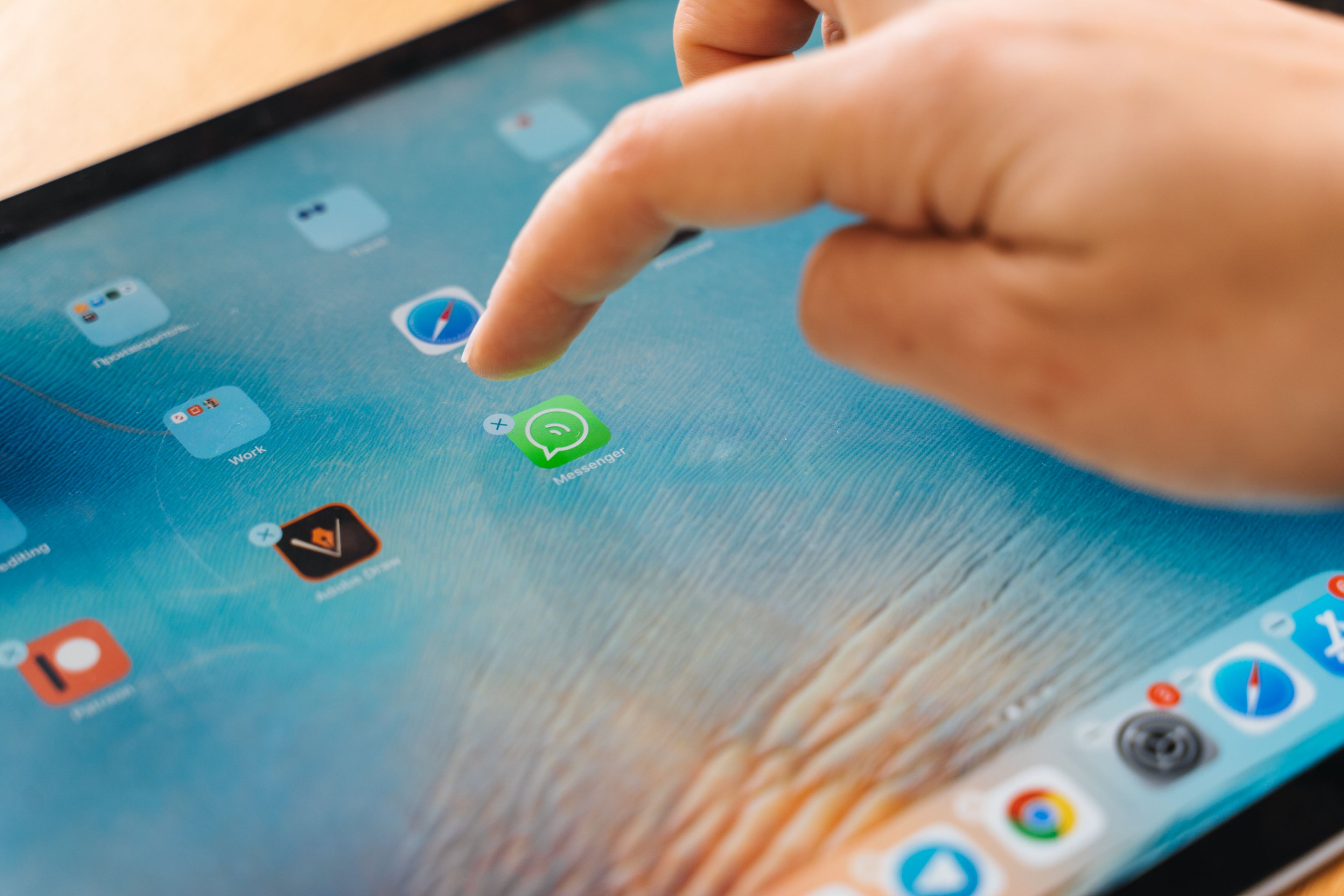 Varias aplicaciones en una tablet con una mano tocando WhatsApp