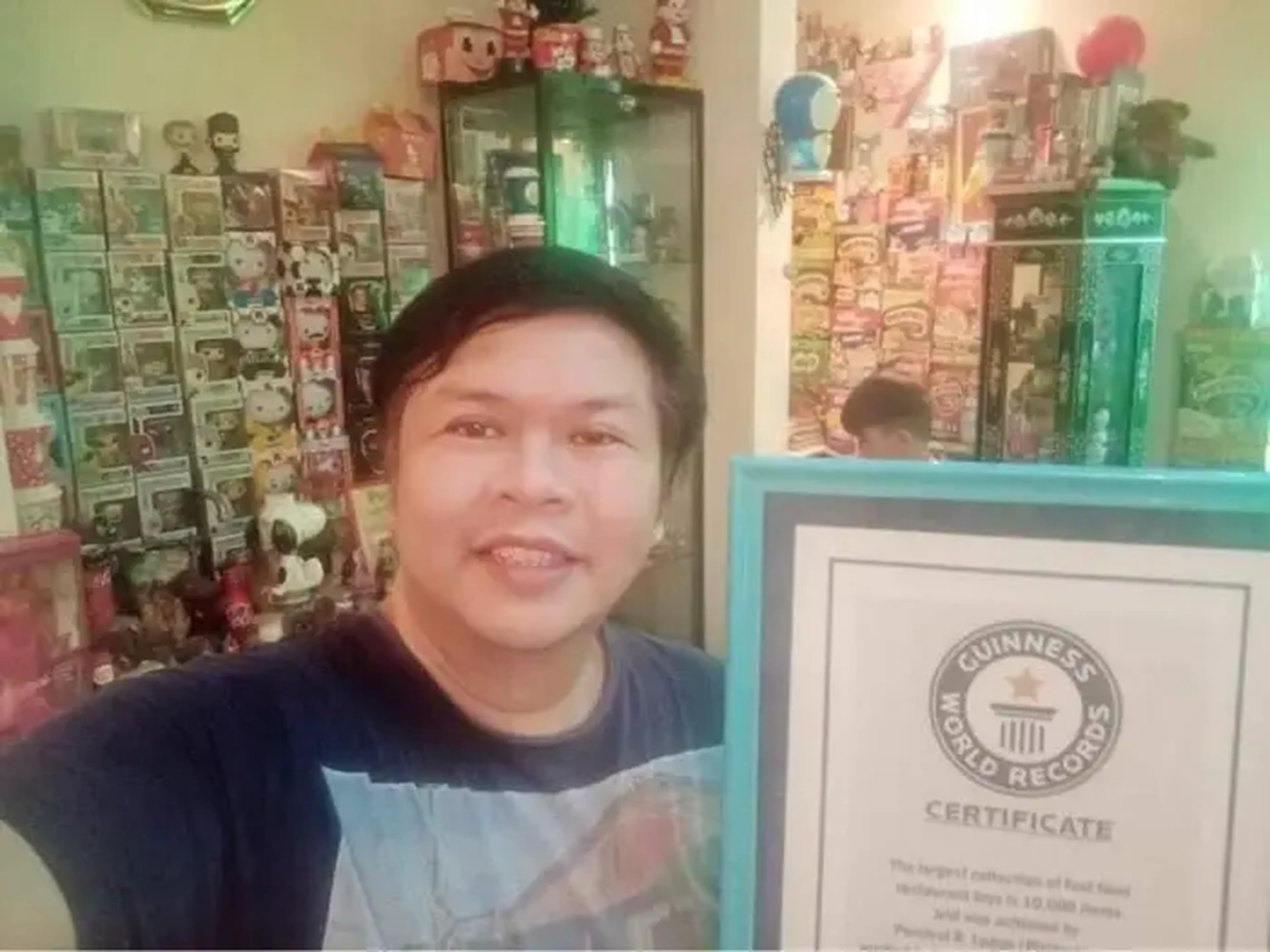 Percival R. Lugue posando con su Guinness World Record por el mayor número de juguetes de comida rápida que ganó en 2014.