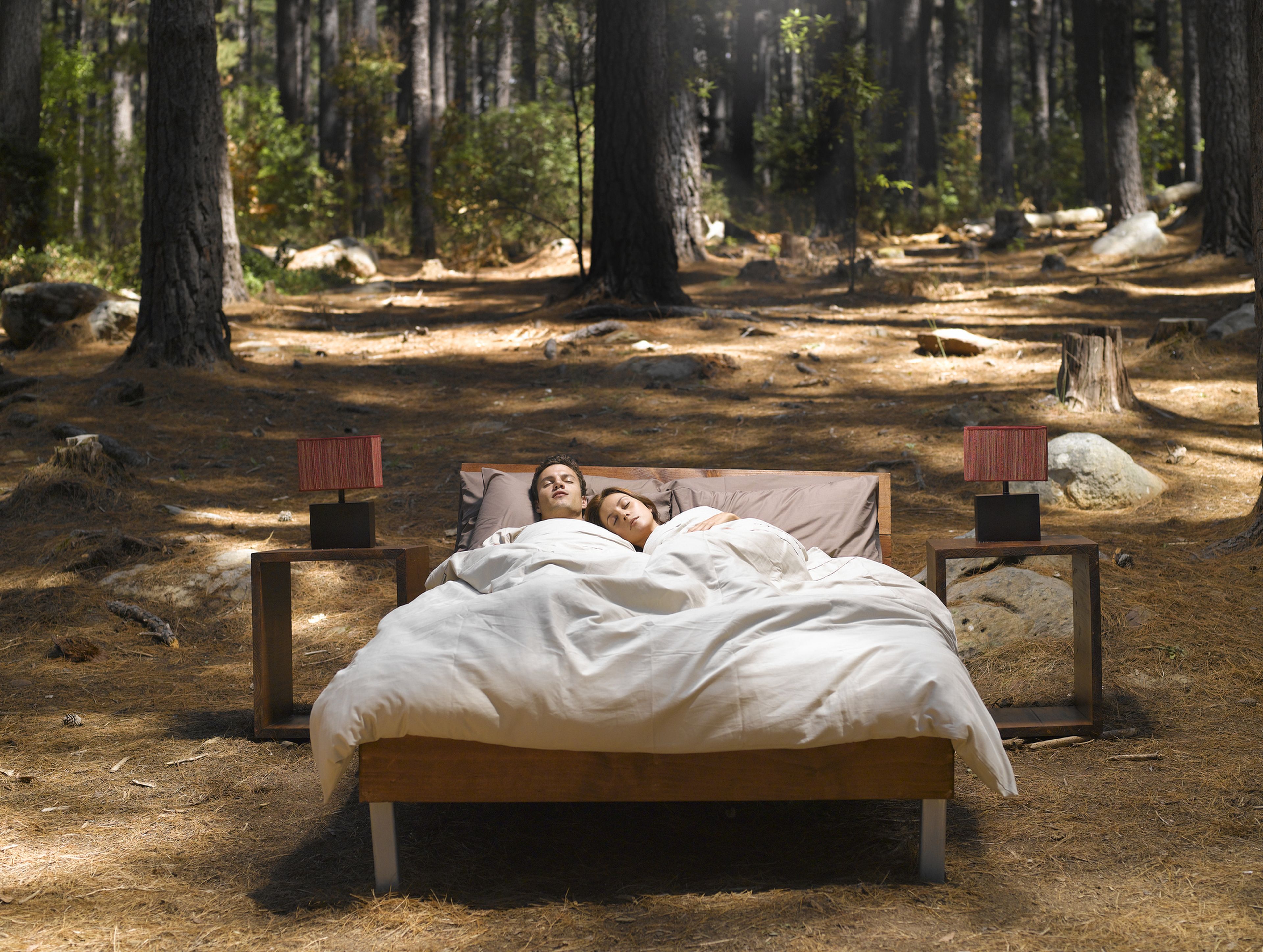 2 personas duermen en una cama en medio del campo.