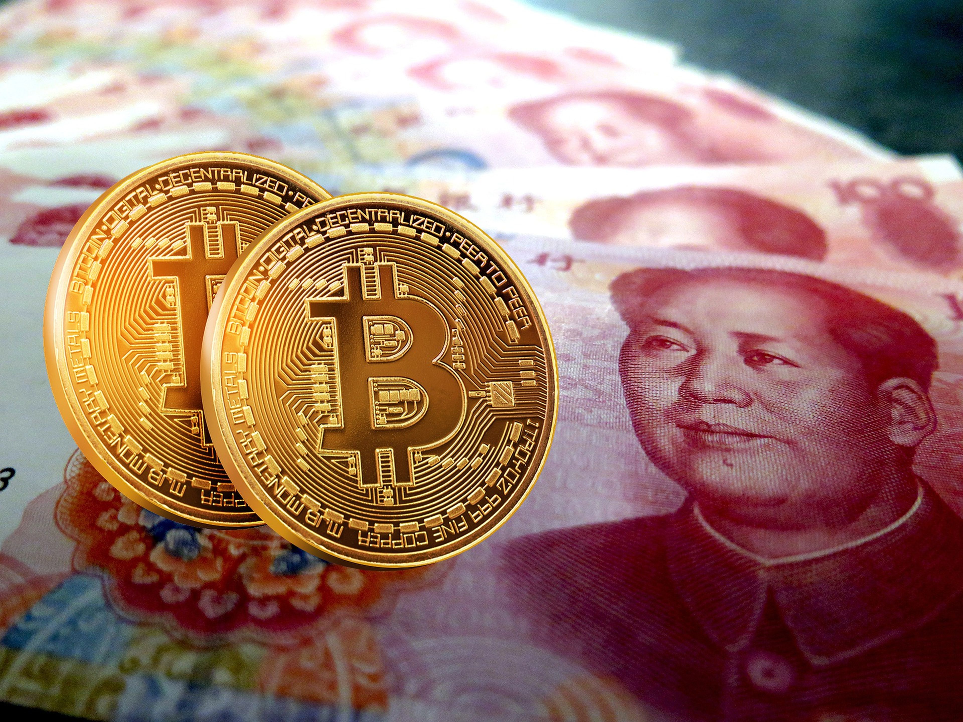 Un billete de curso legal en China junto a dos bitcoins.
