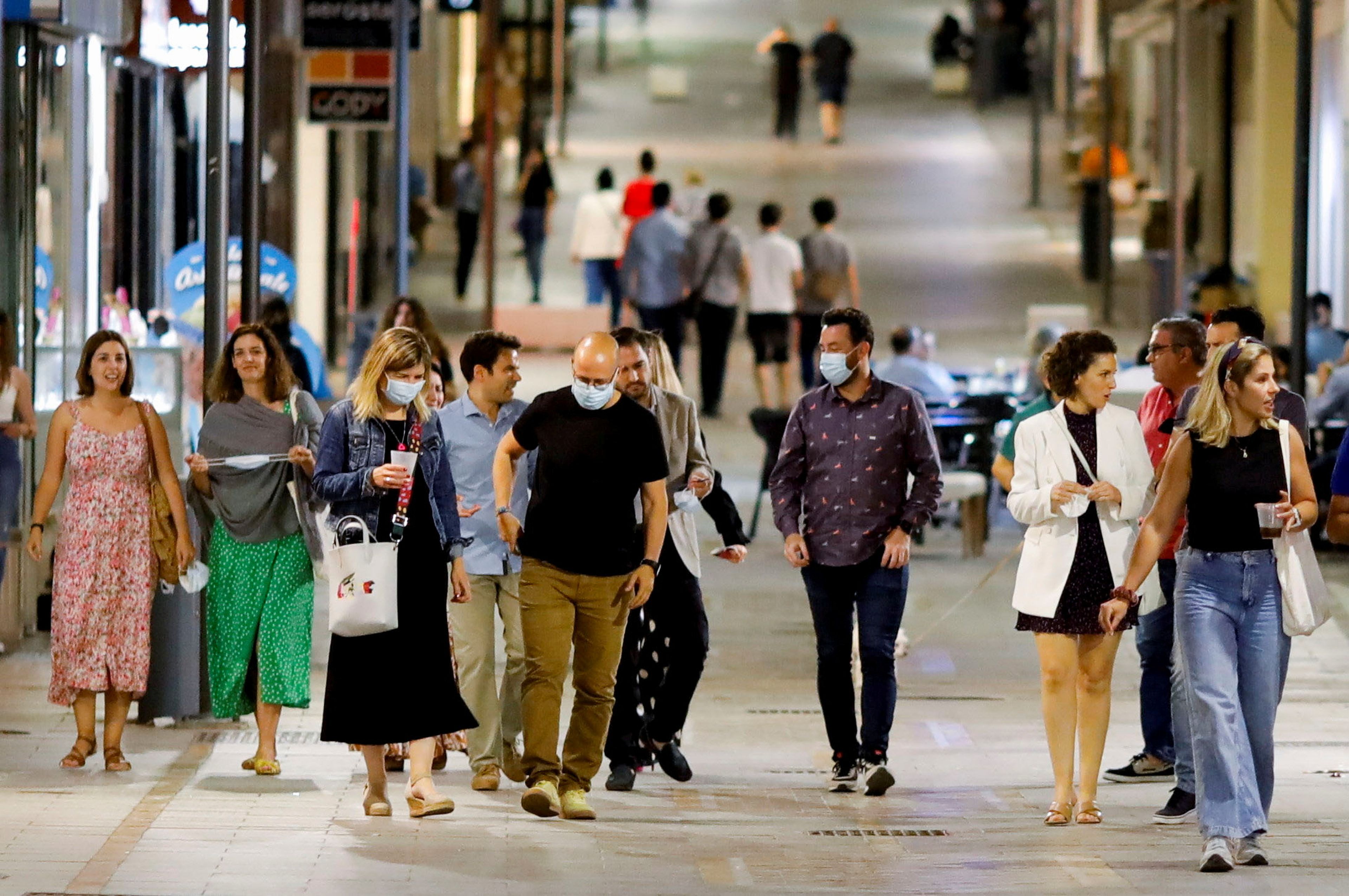 Personas con y sin mascarillas caminan por una calle española, tras la entrada en vigor de la nueva medida que permite no llevarla en exteriores.