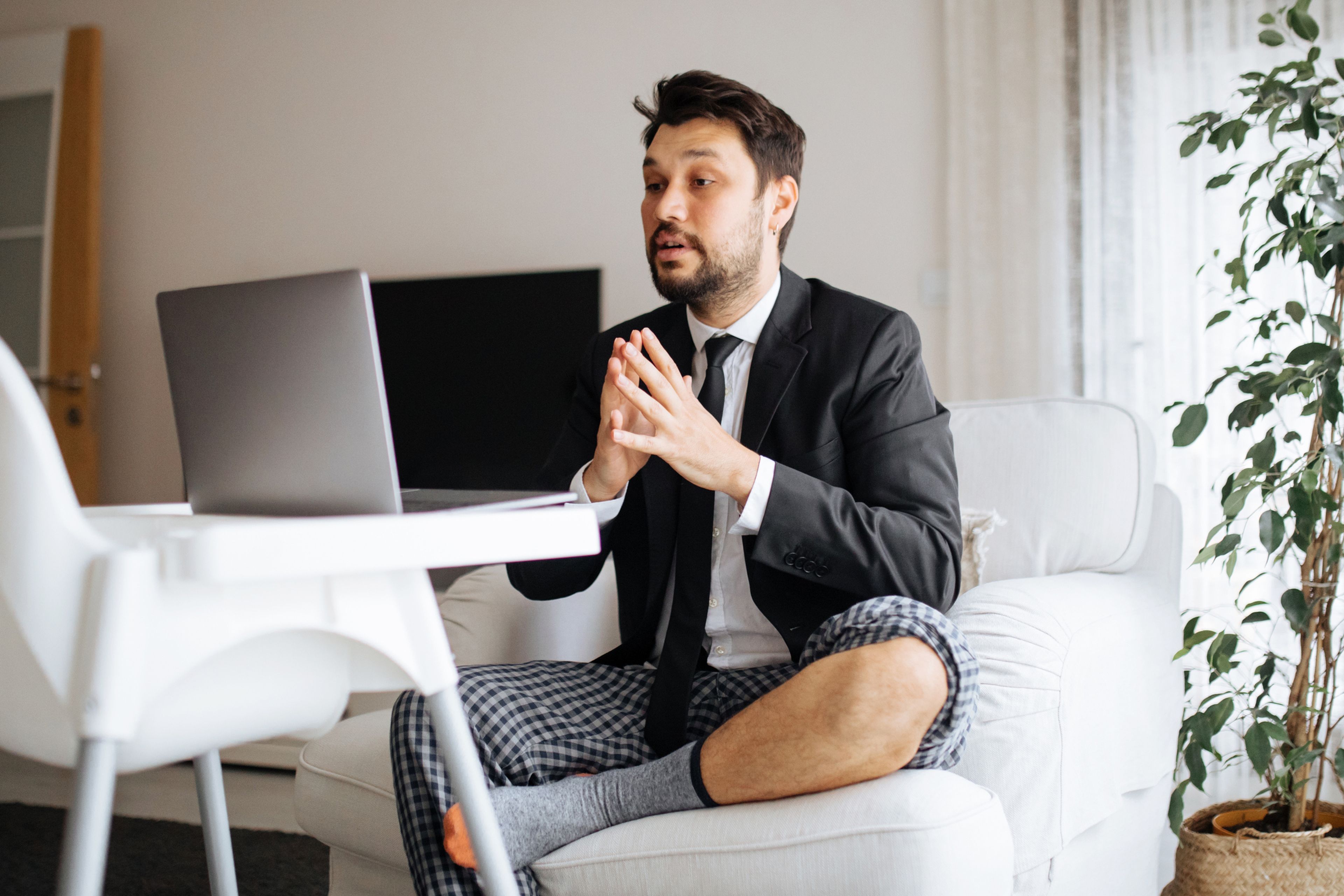 Un hombre con americana, corbata y pantalón de pijama delante del ordenador.