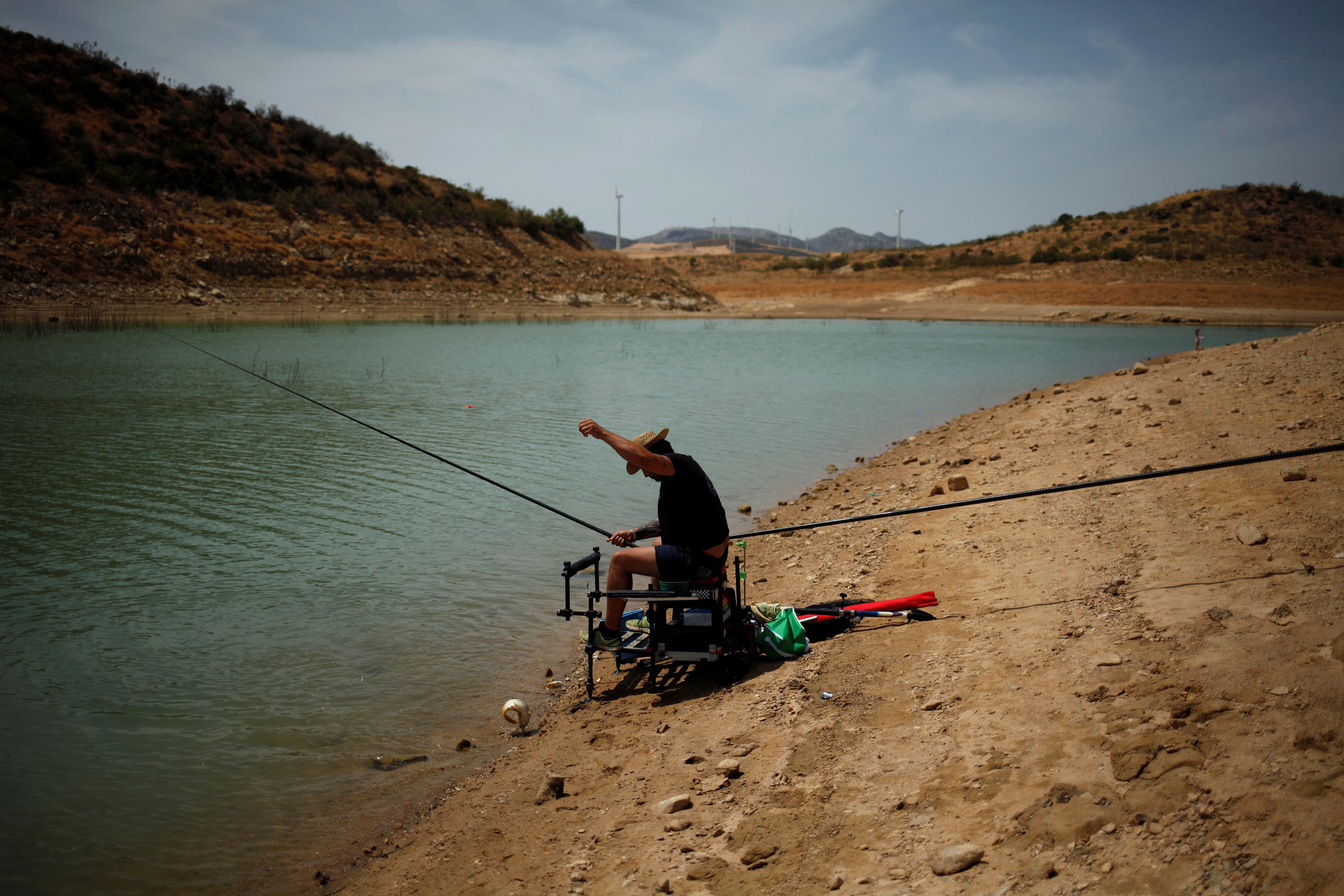 Un hombre pescando en un pantano casi seco