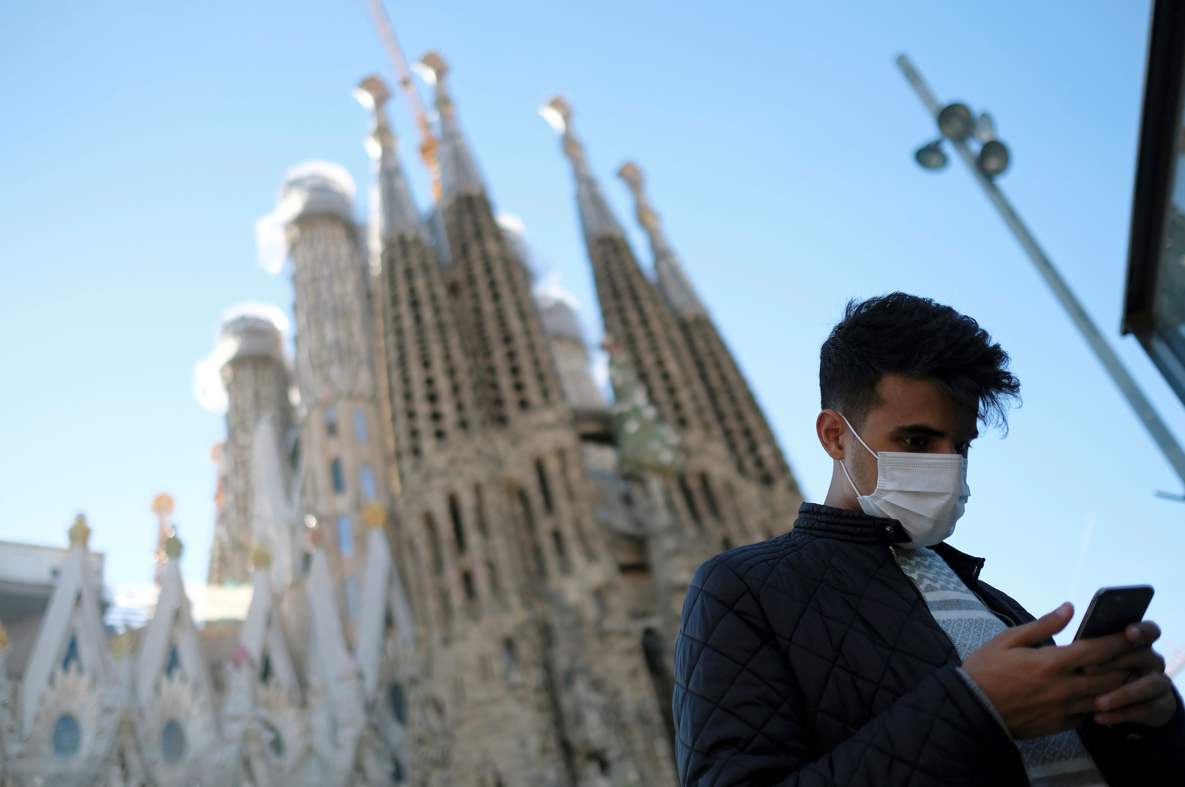 Un hombre con un smartphone delante de la Sagrada Familia de Barcelona.