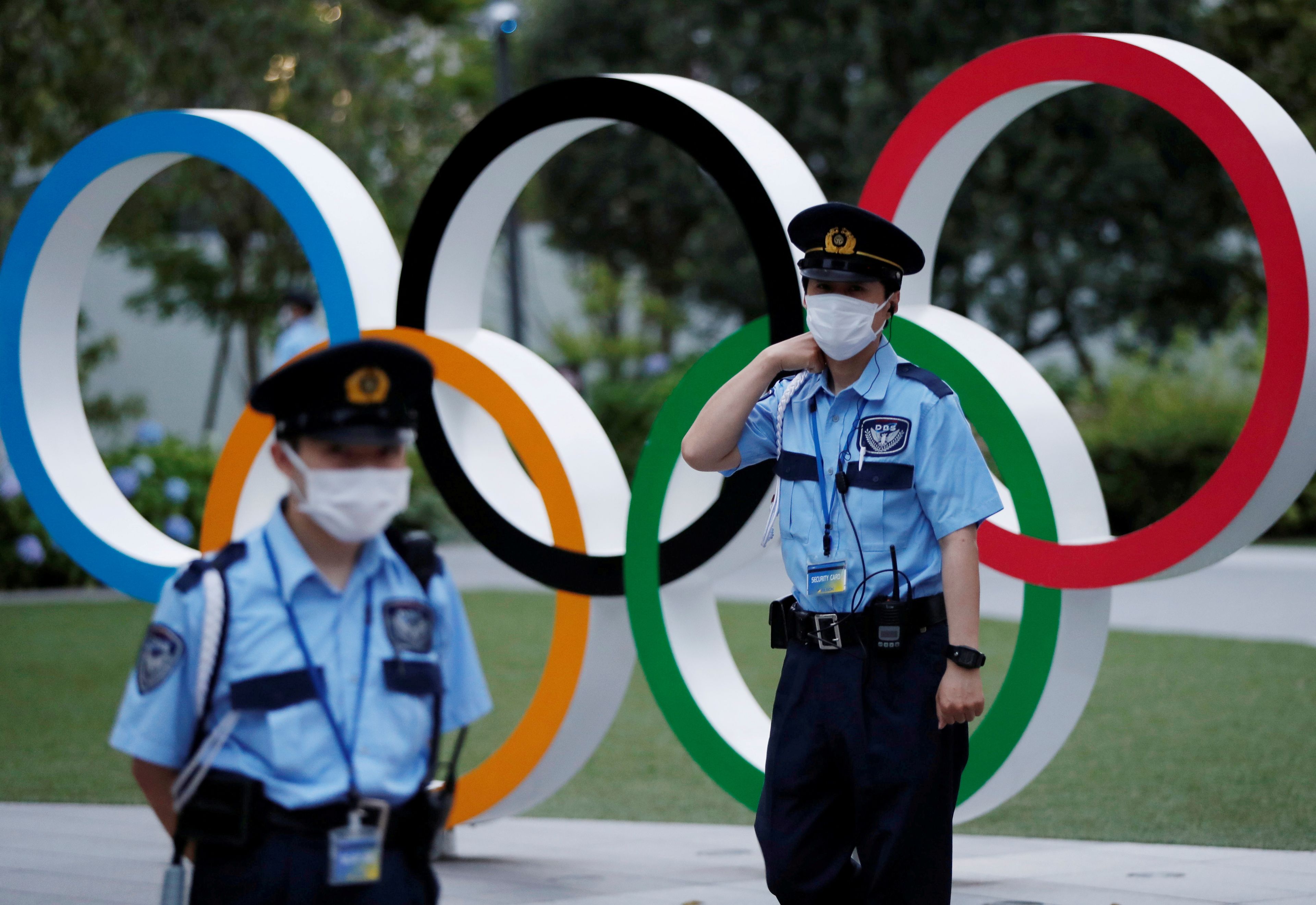 Dos guardias de seguridad frente al logo de los Juegos Olímpicos en Tokio.