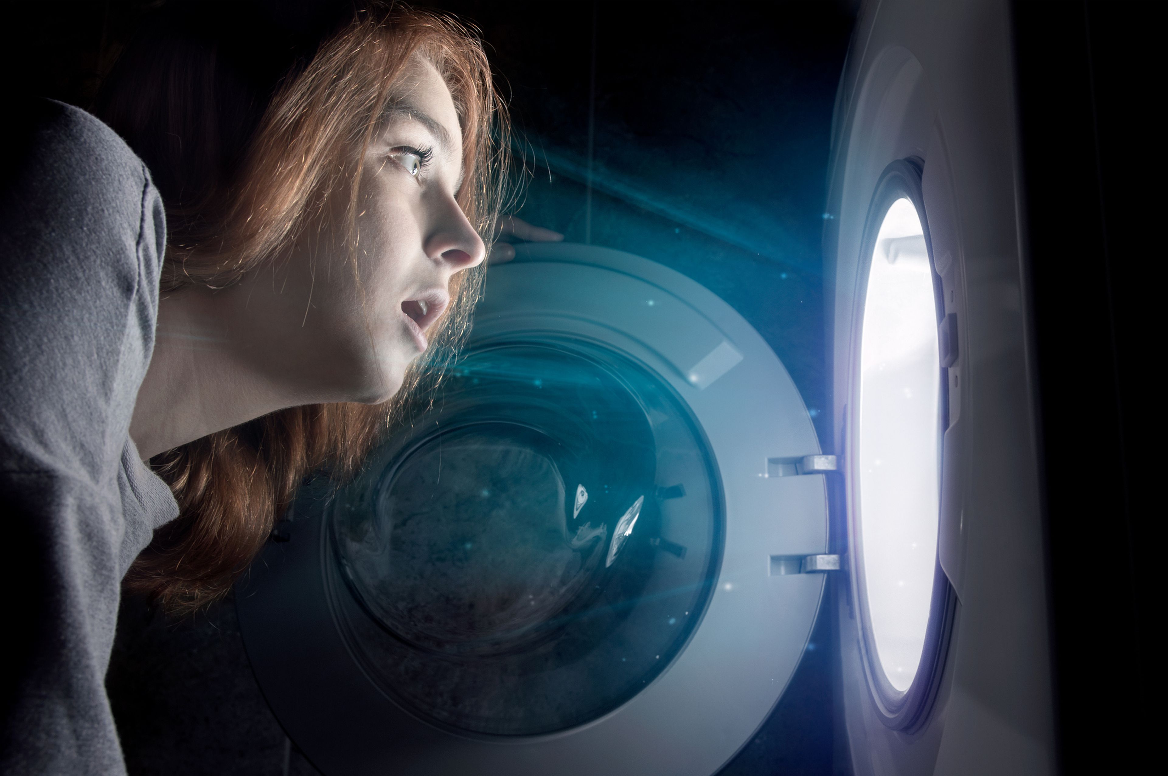 Una mujer mira en el interior de la lavadora.