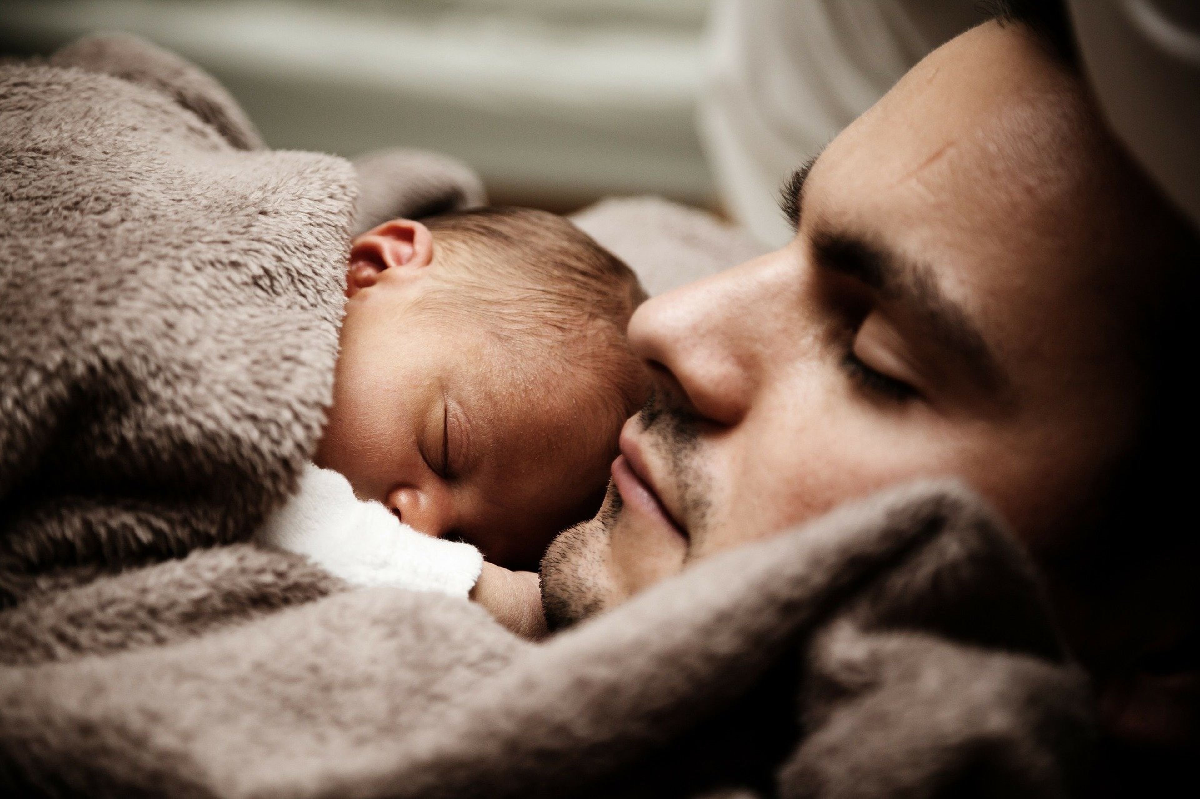 Un padre duerme con su bebé.