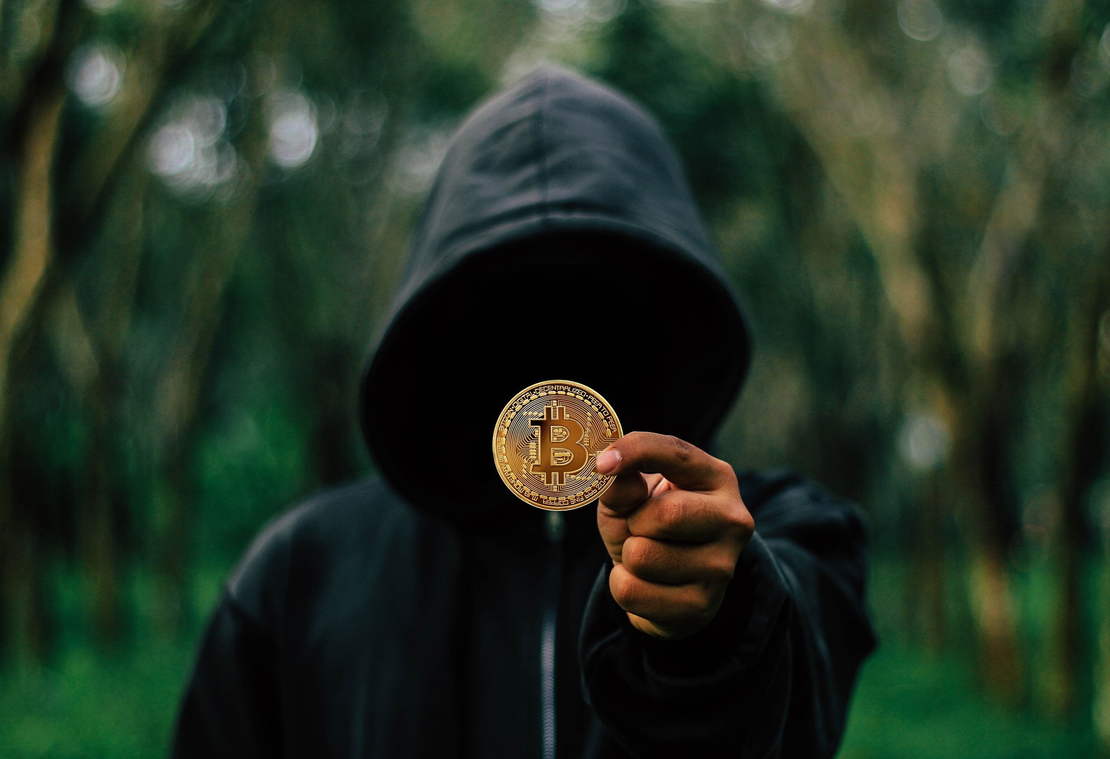 Una persona con la cara oculta muestra un bitcoin.