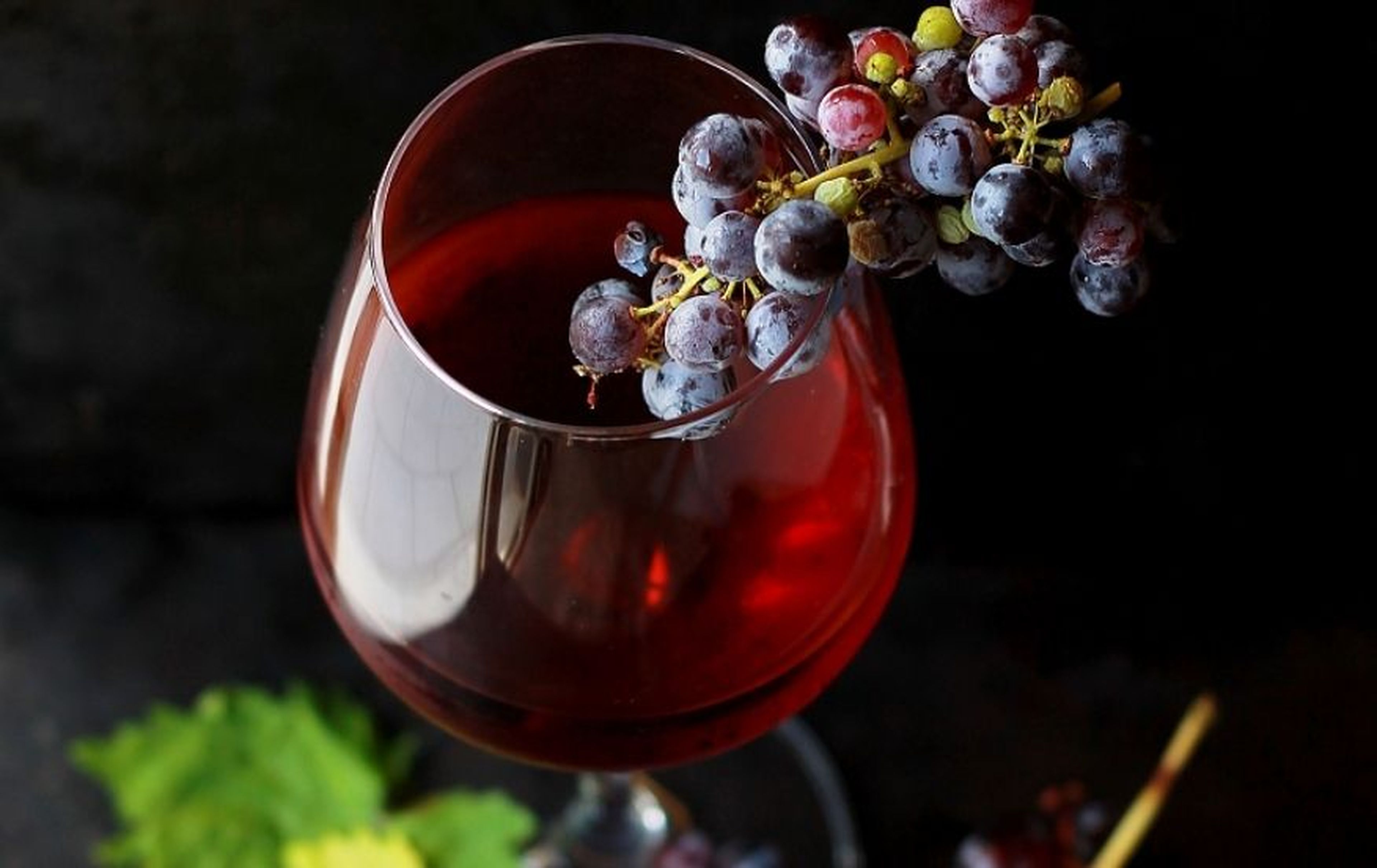 Un racimo de uvas sobre una copa de vino.