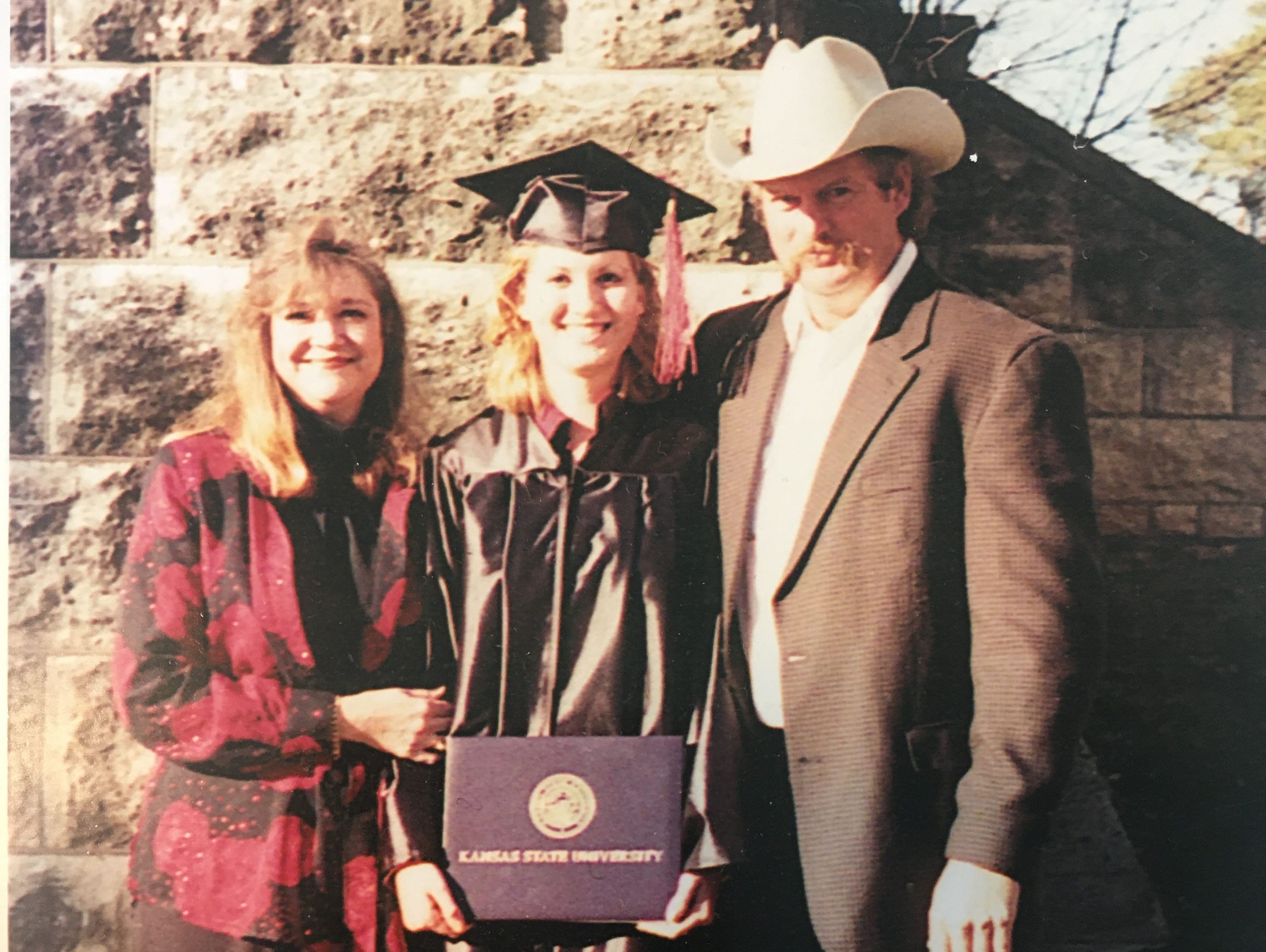 La autora en el centro junto a sus padres tras graduarse.