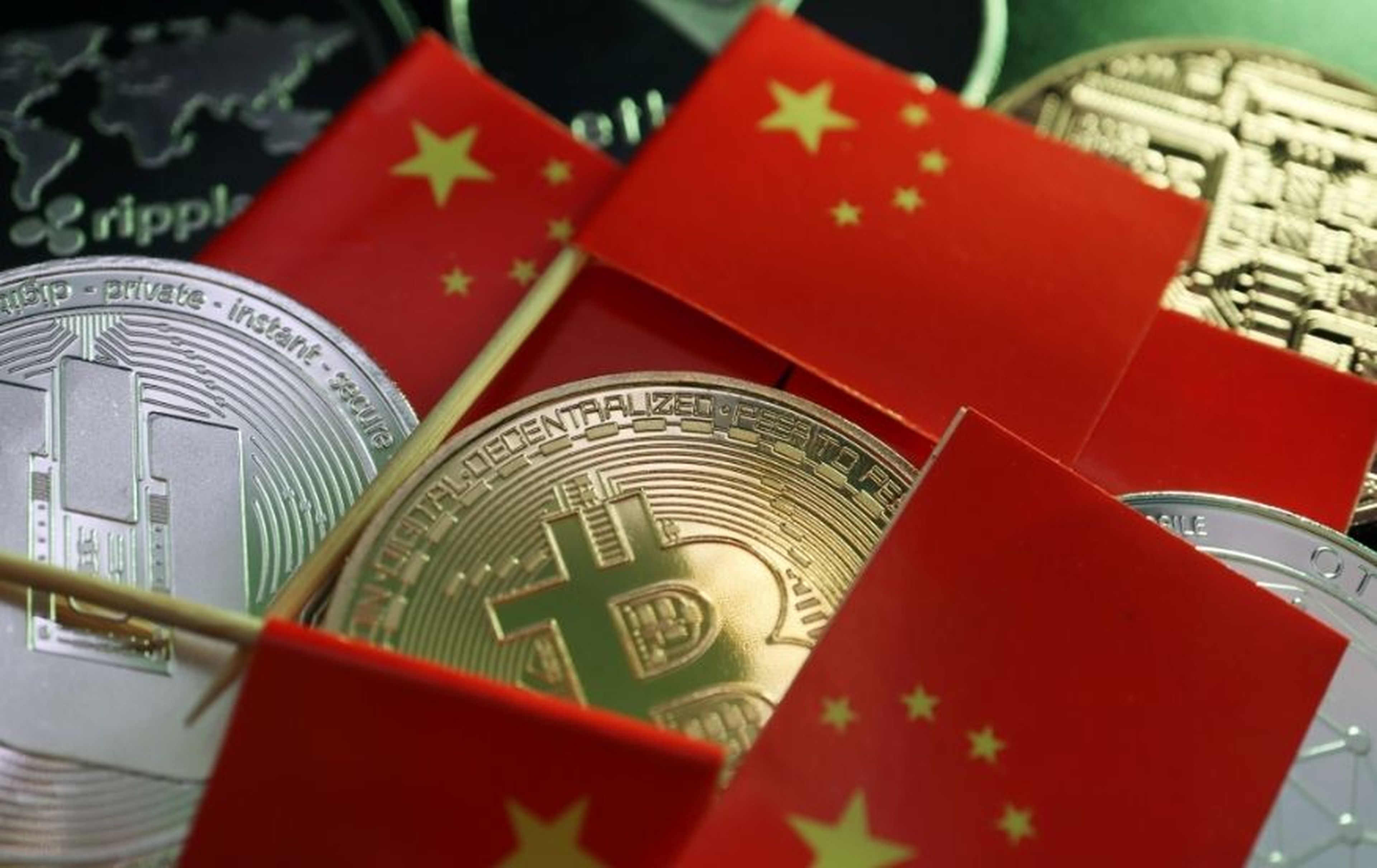 Varias monedas de bitcoin junto a banderas de China.