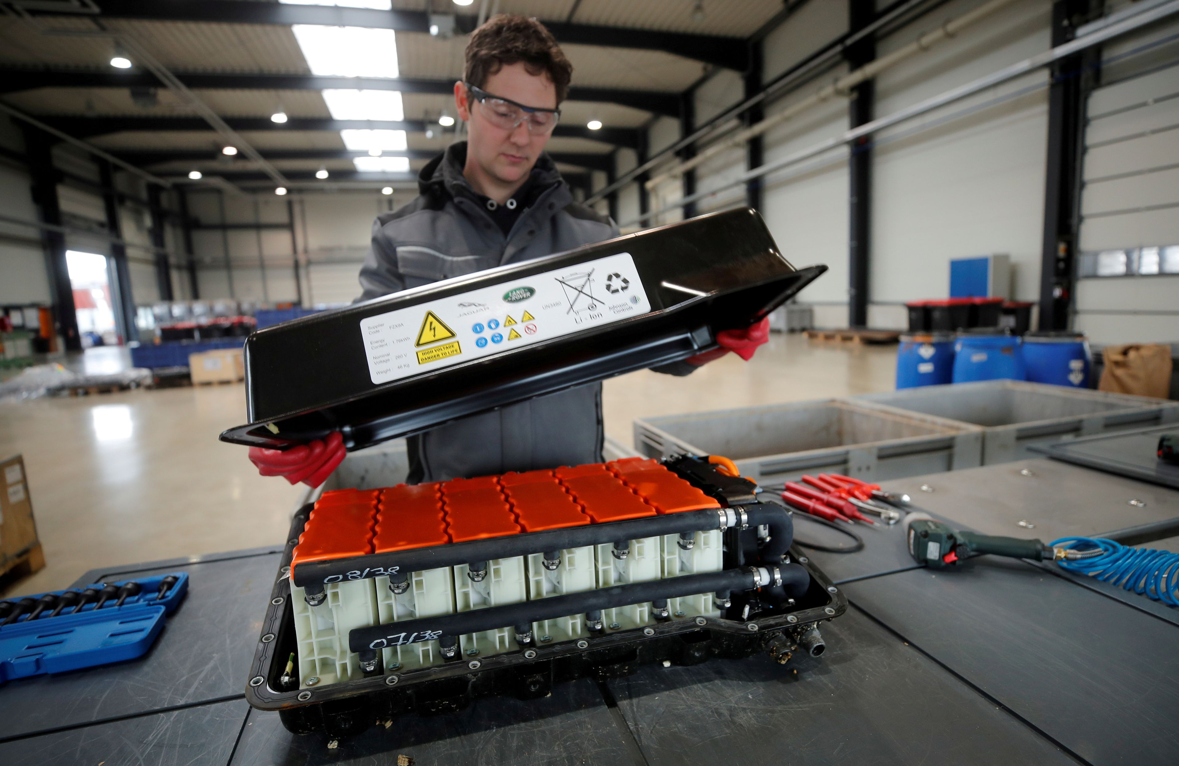 Un operario desmonta una batería de litio de vehículo usada en una fábrica alemana.