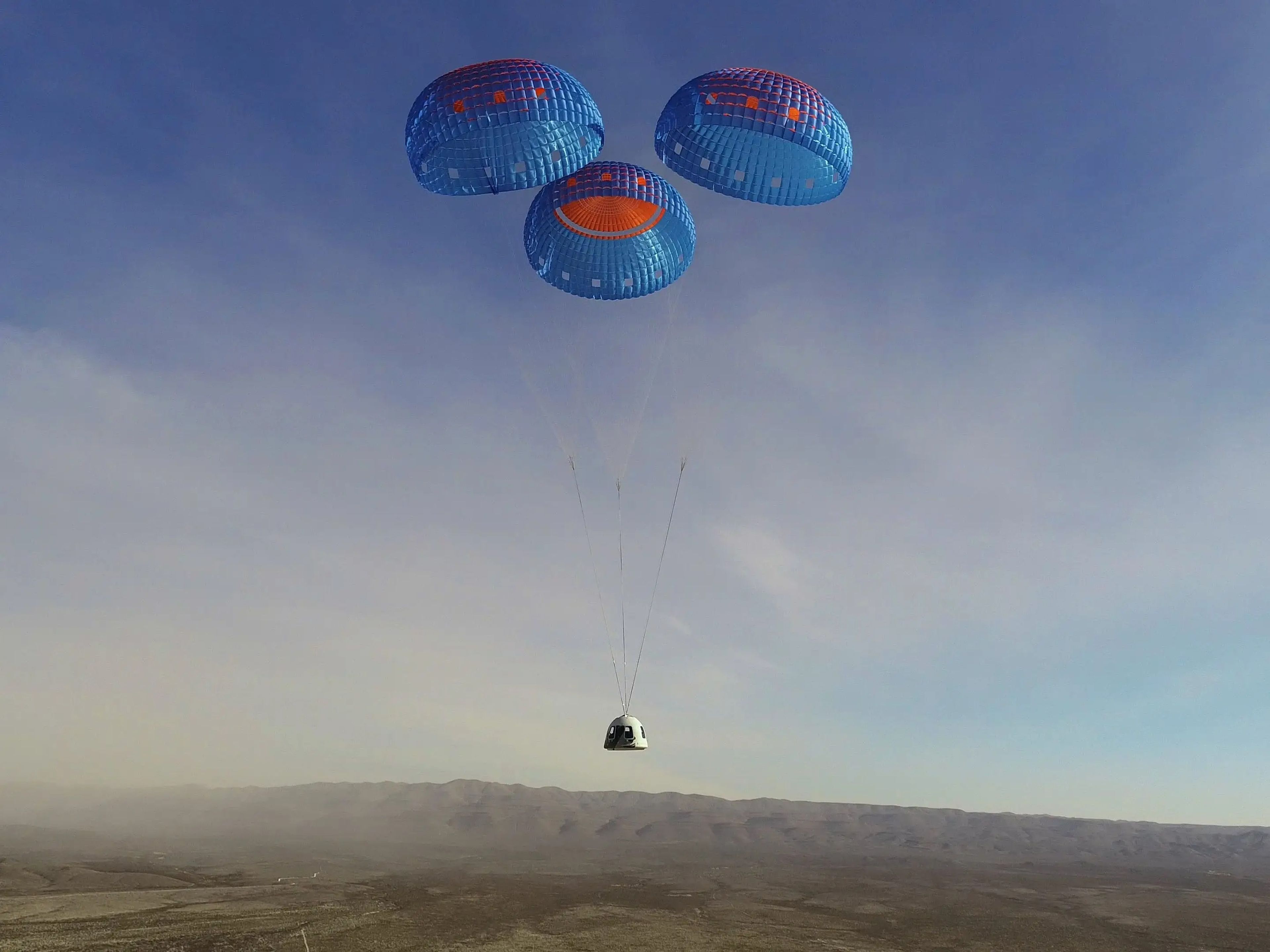 La cápsula de la tripulación de New Shepard se lanza en paracaídas a un aterrizaje en el sitio de lanzamiento uno de Blue Origin en Texas el 14 de enero.