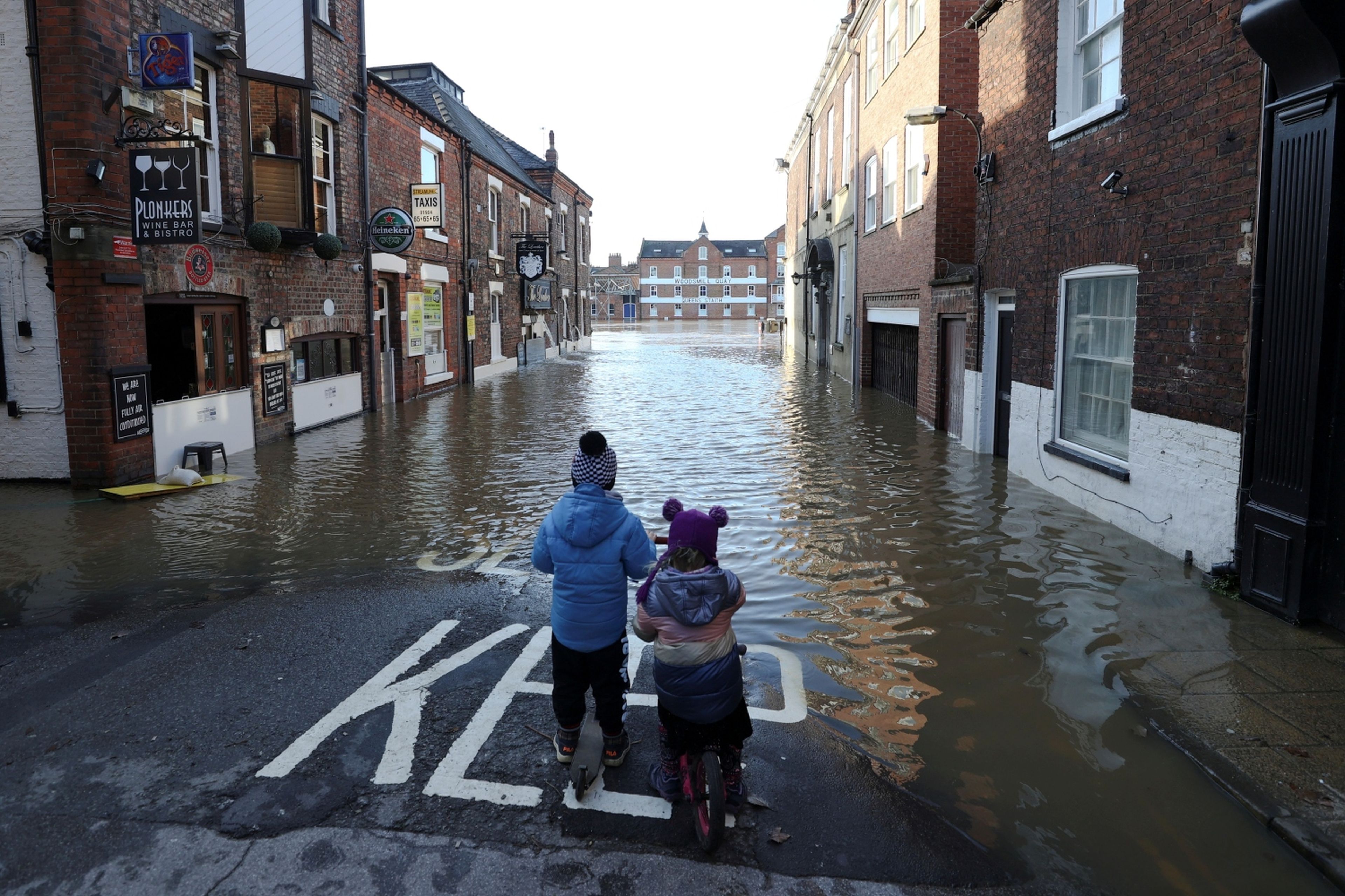 Dos niños parados en una calle parcialmente inundada después de que el río Ouse se desborde en York (Gran Bretaña).