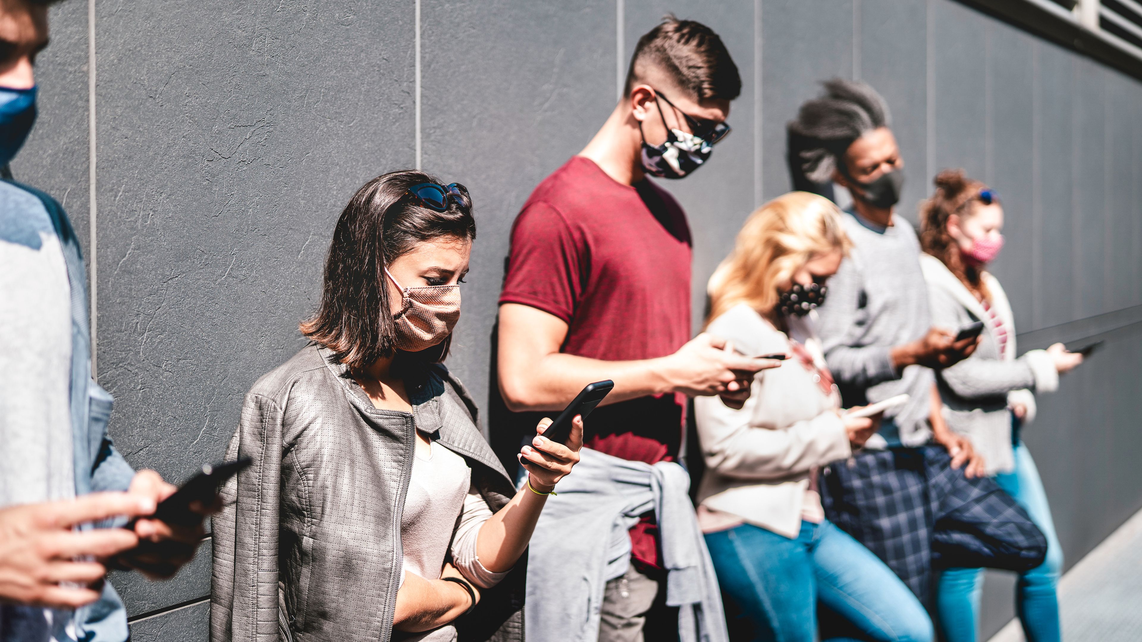 Un grupo de jóvenes mira su teléfono móvil en la calle durante la pandemia