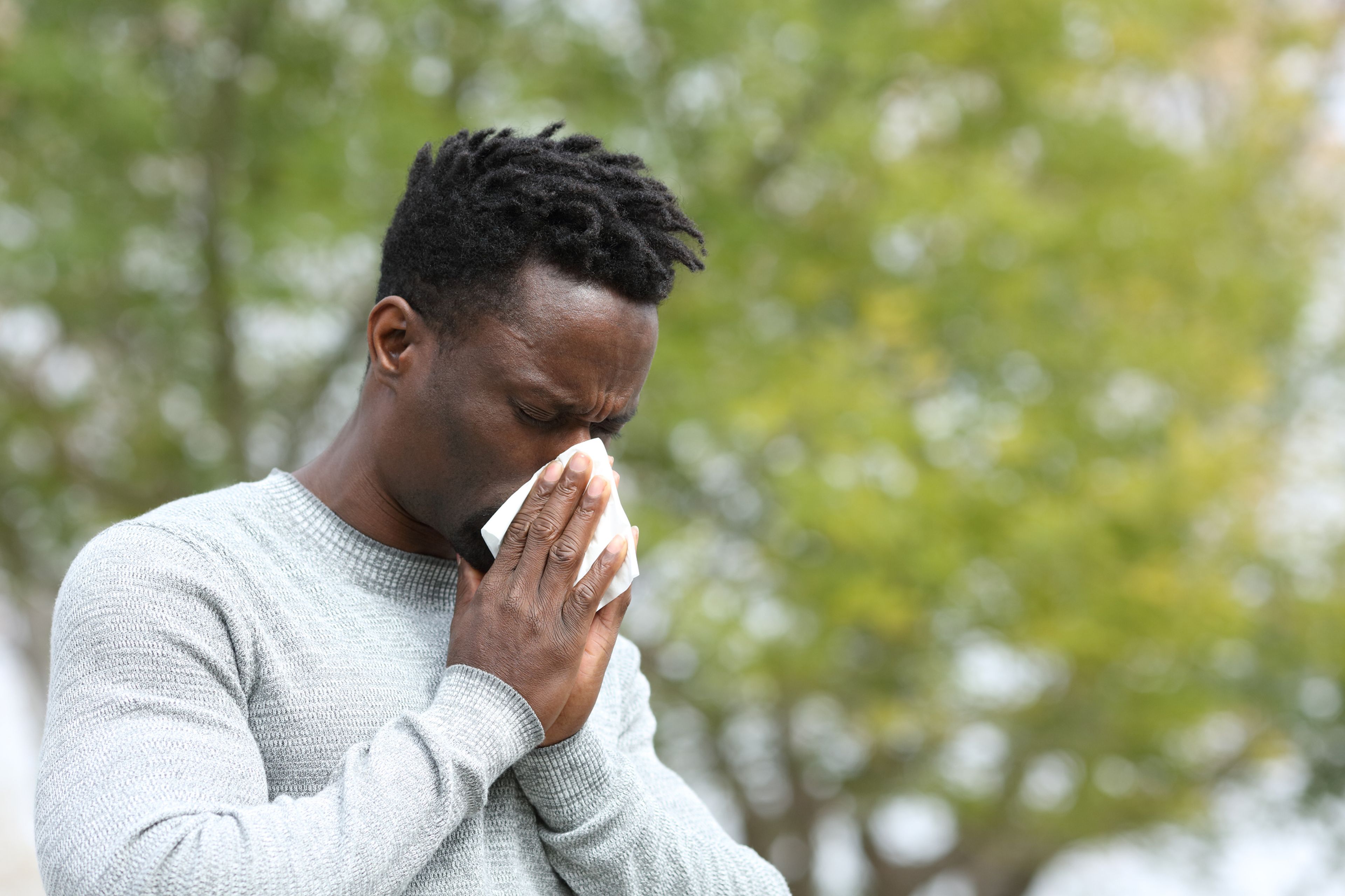 Un hombre estornuda por un resfriado.