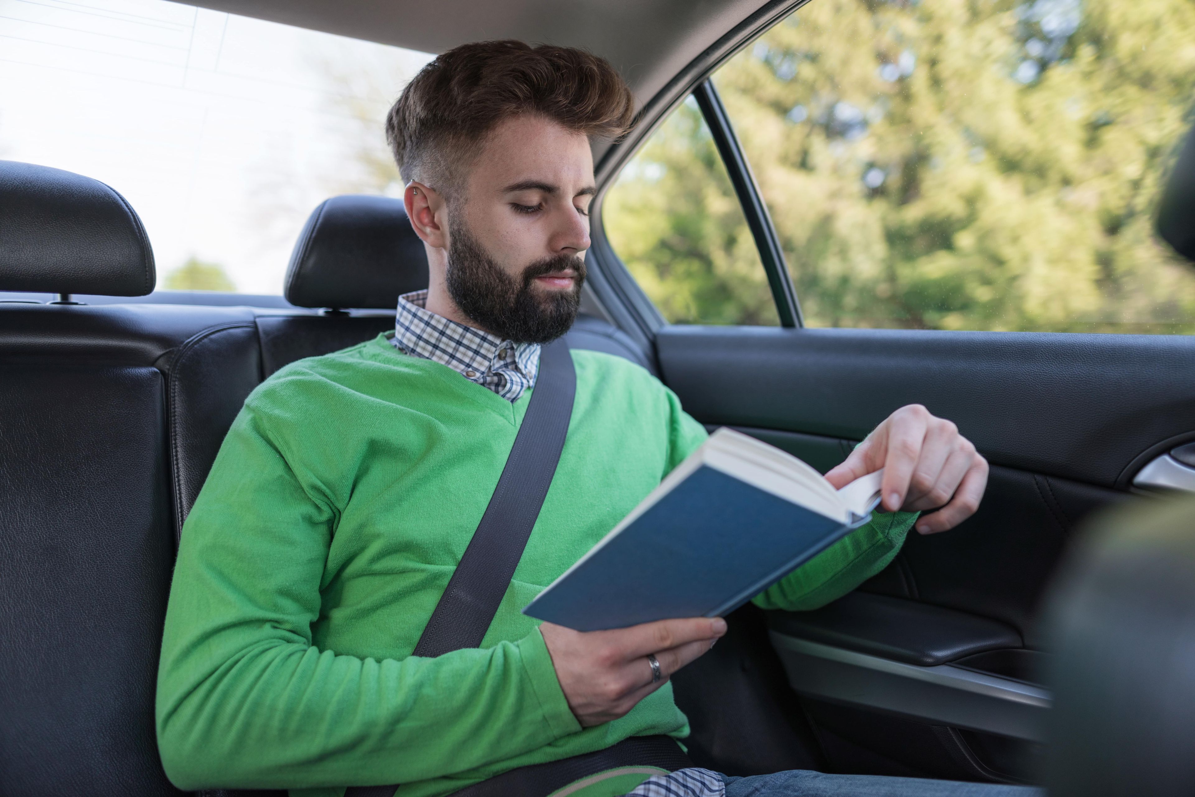 Un hombre lee un libro en un coche